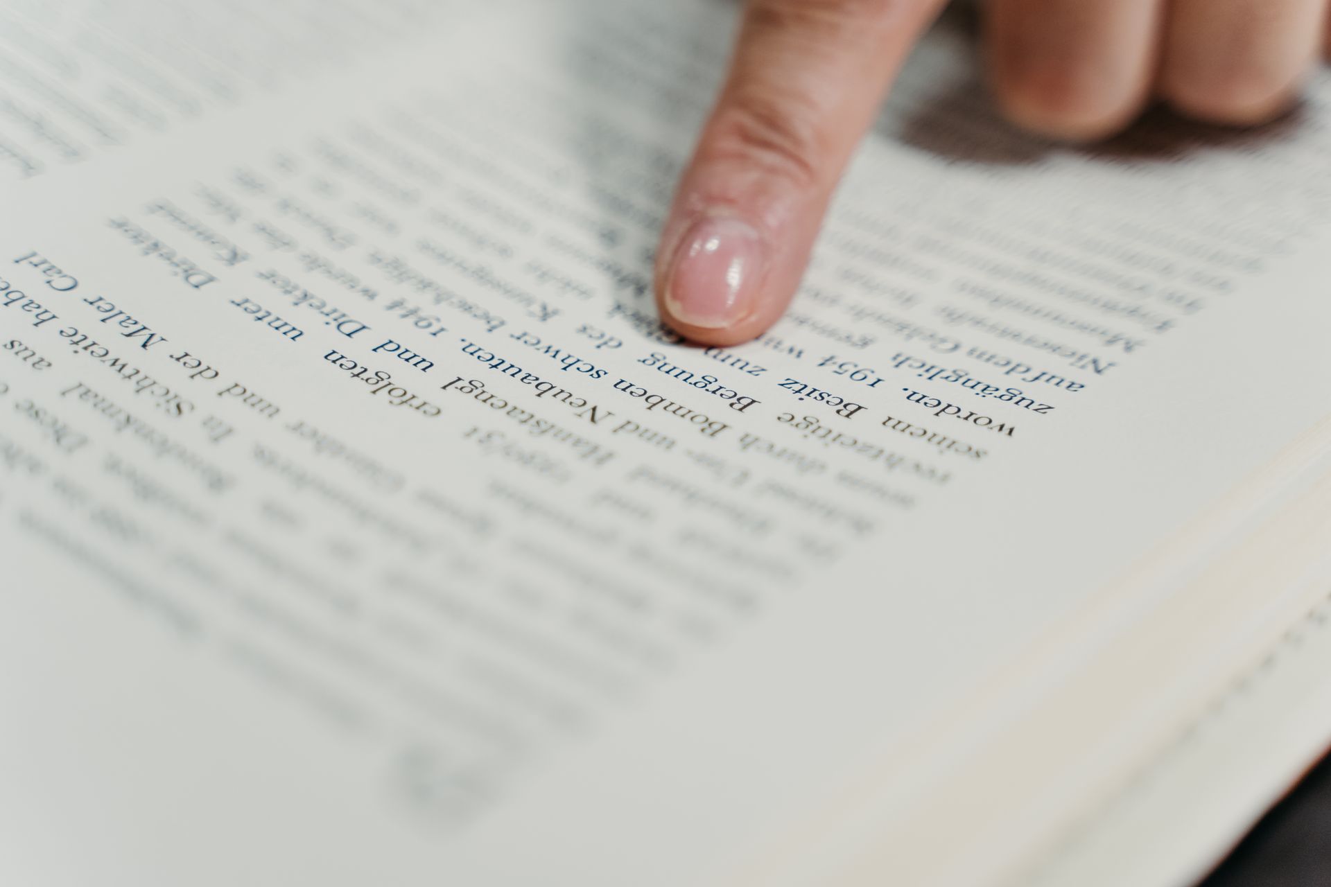 Finger pointing at text on a book page