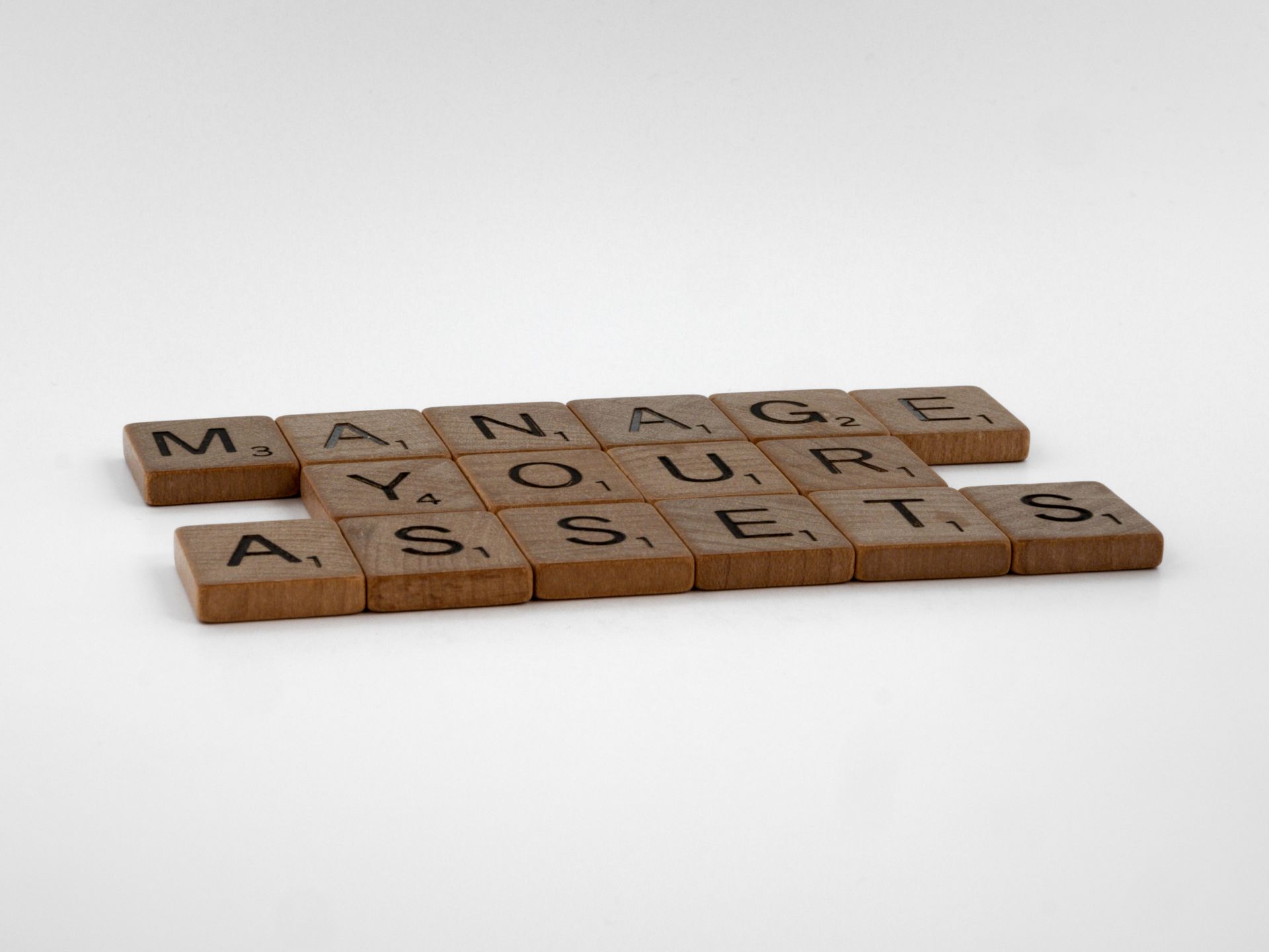 Wooden Scrabble tiles spelling Manage Your Assets