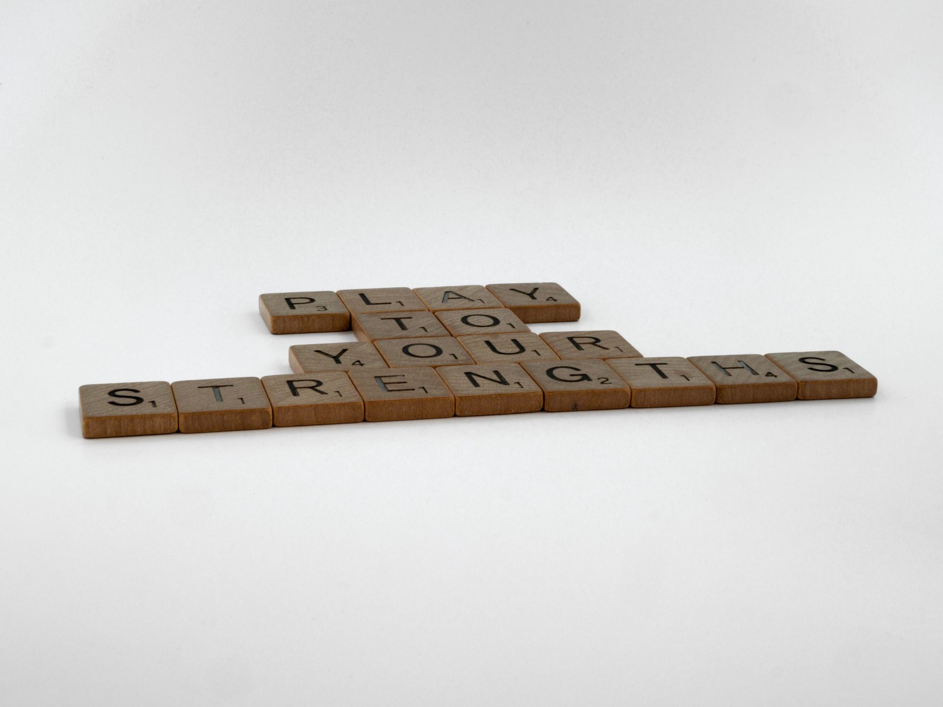 Wooden Scrabble tiles spelling Play to your strengths