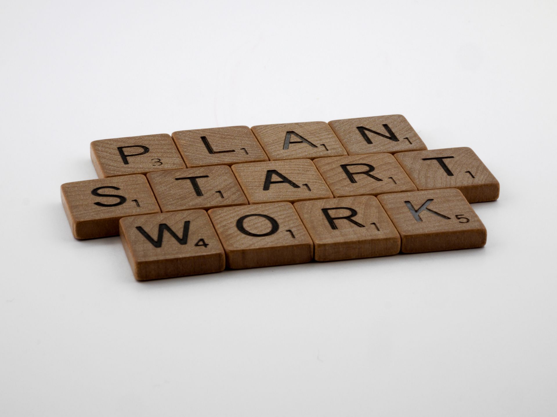 Scrabble tiles spelling Plan Start Work on a white surface