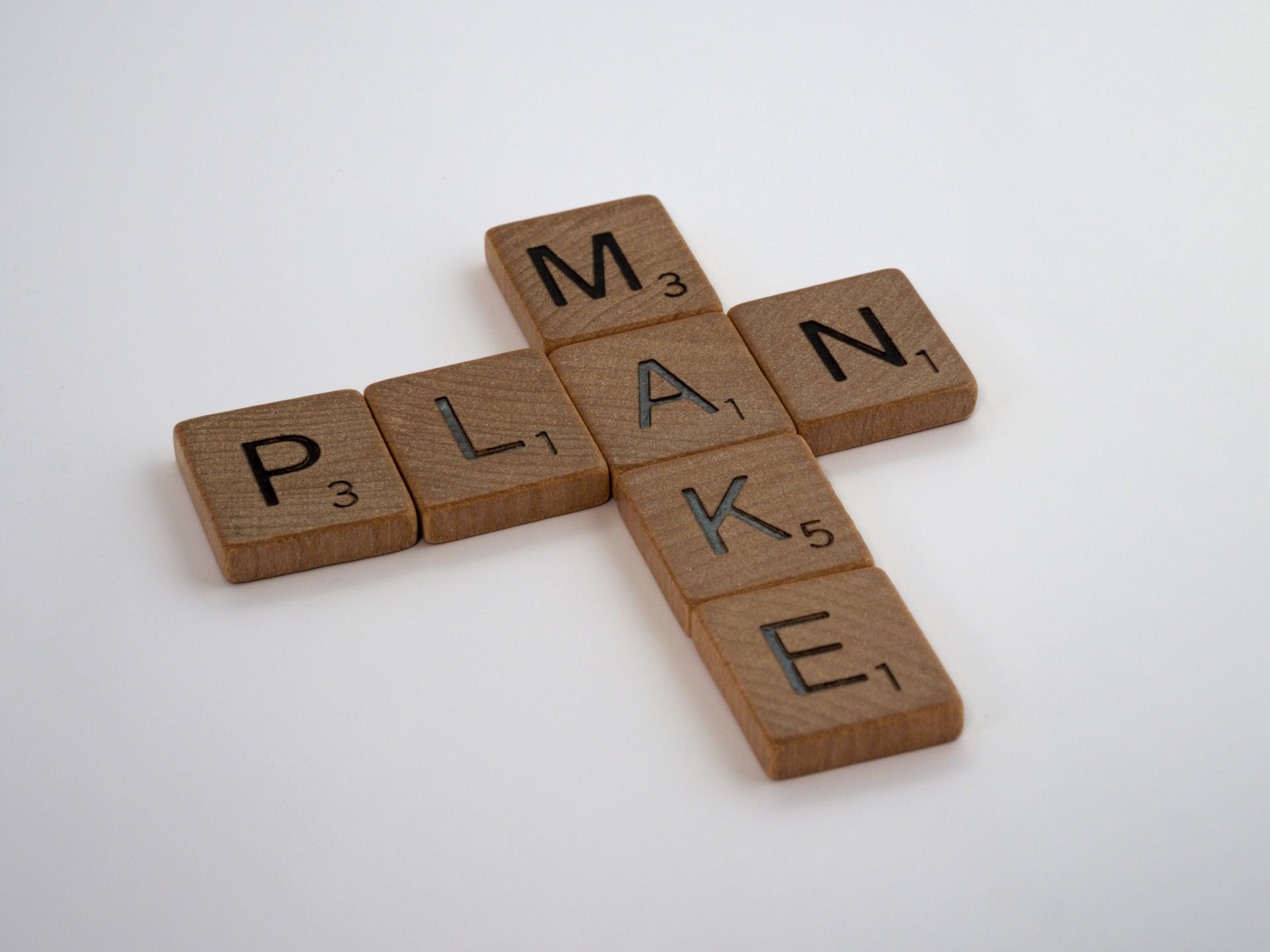 Wooden Scrabble tiles spelling the words make and plan