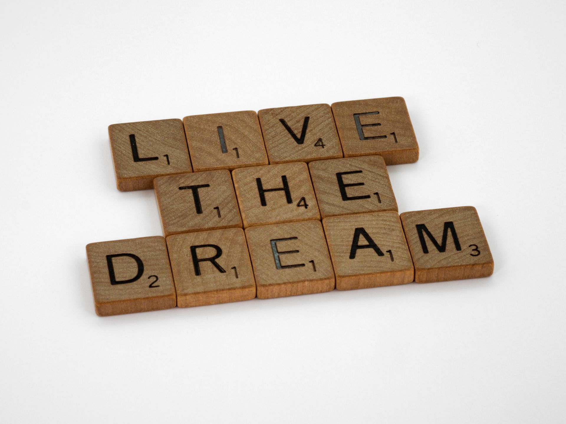 Scrabble tiles spelling Live The Dream on a white surface