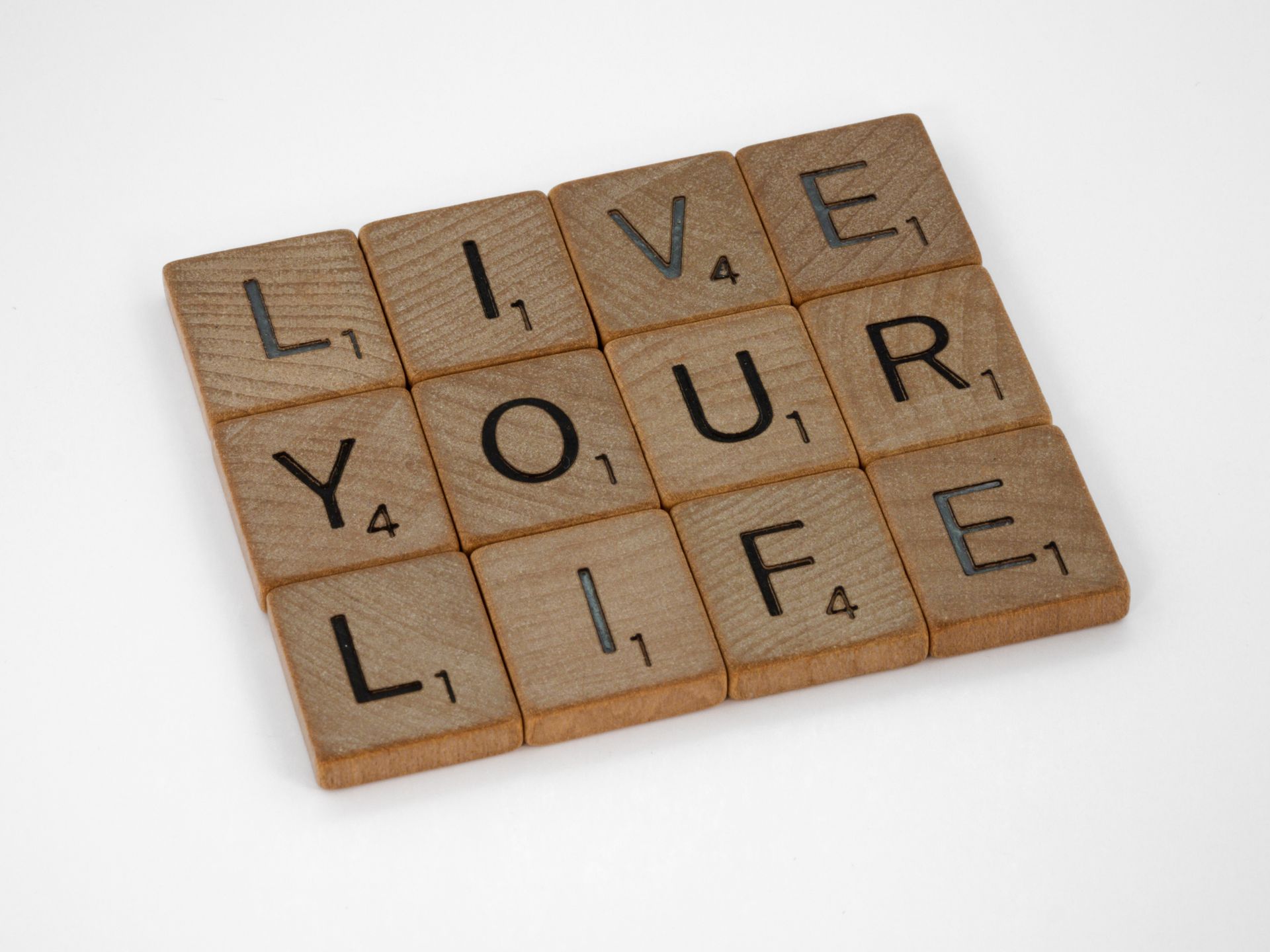 Scrabble tiles spelling Live Your Life on a white background
