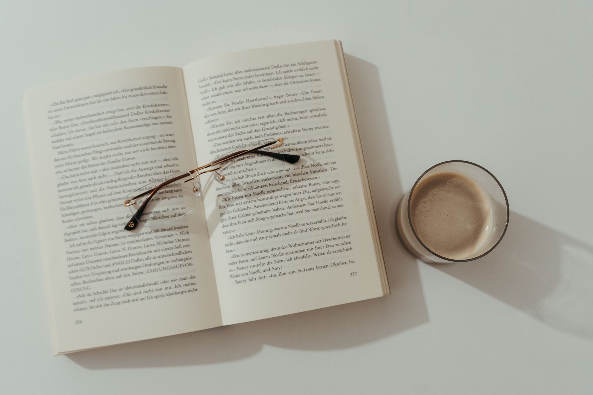 Open book and coffee cup on a white table
