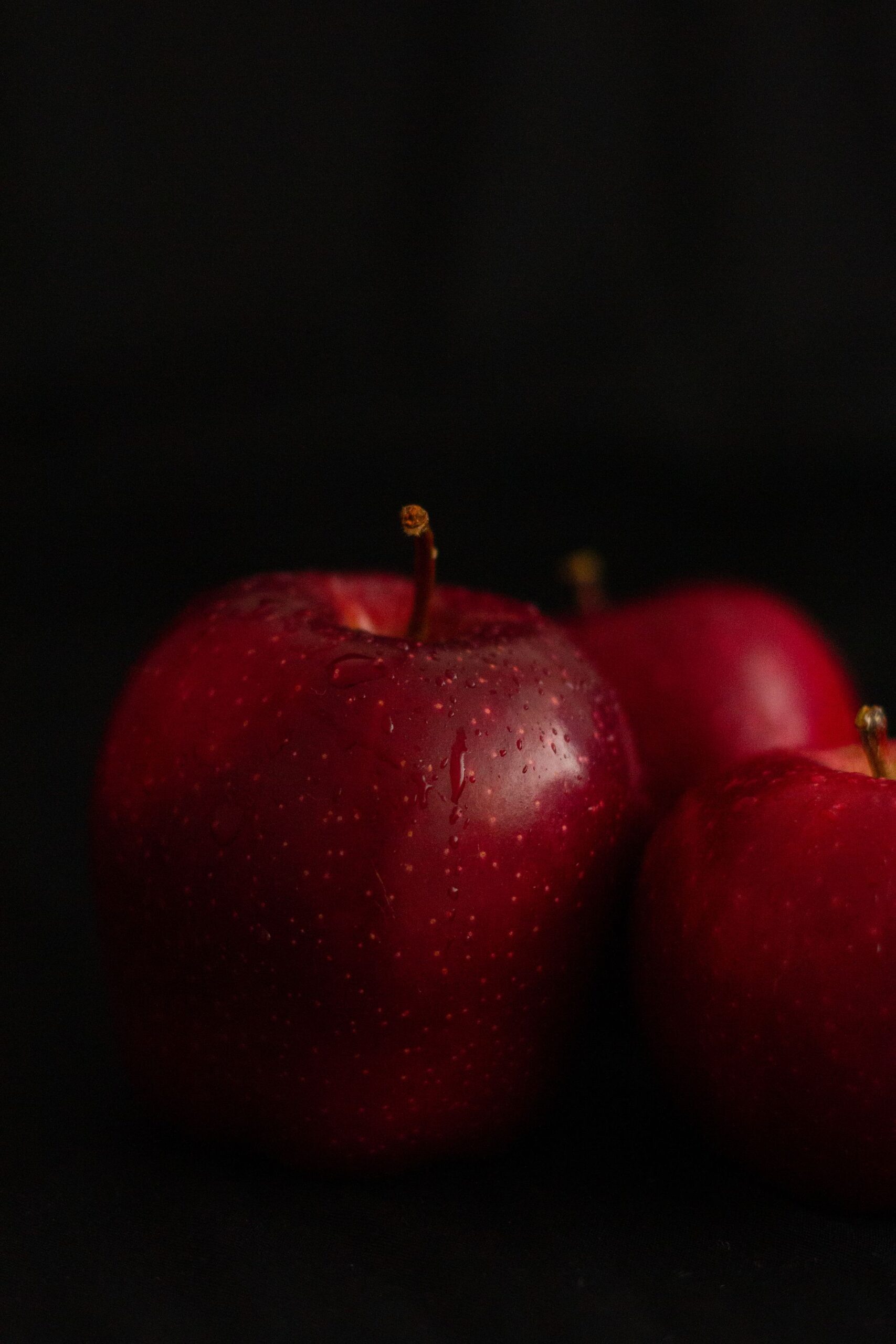 Vibrant red apples with water droplets on a dark background