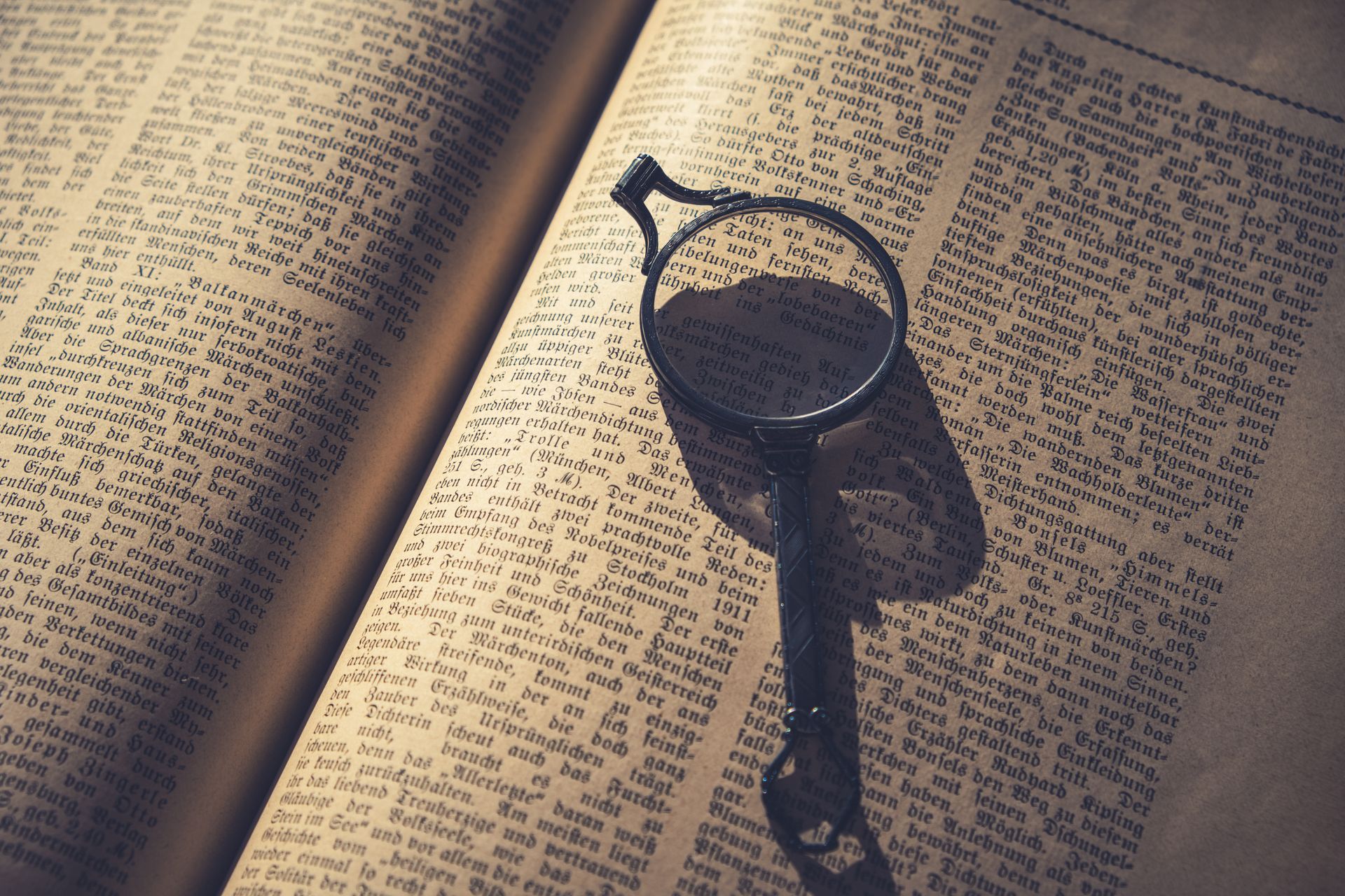 Old book with a magnifying glass in warm light