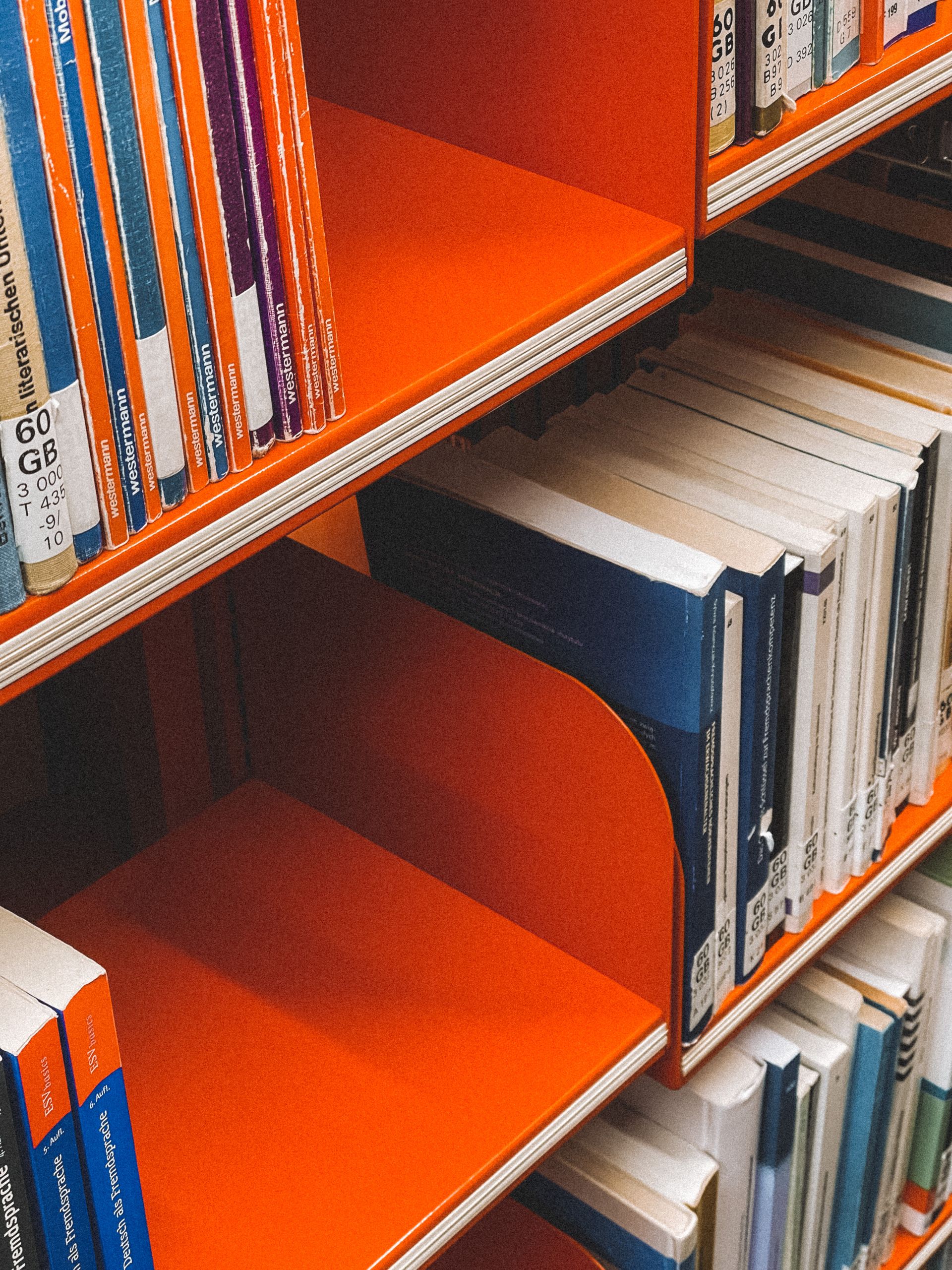 Bright orange bookshelf filled with books in a German library