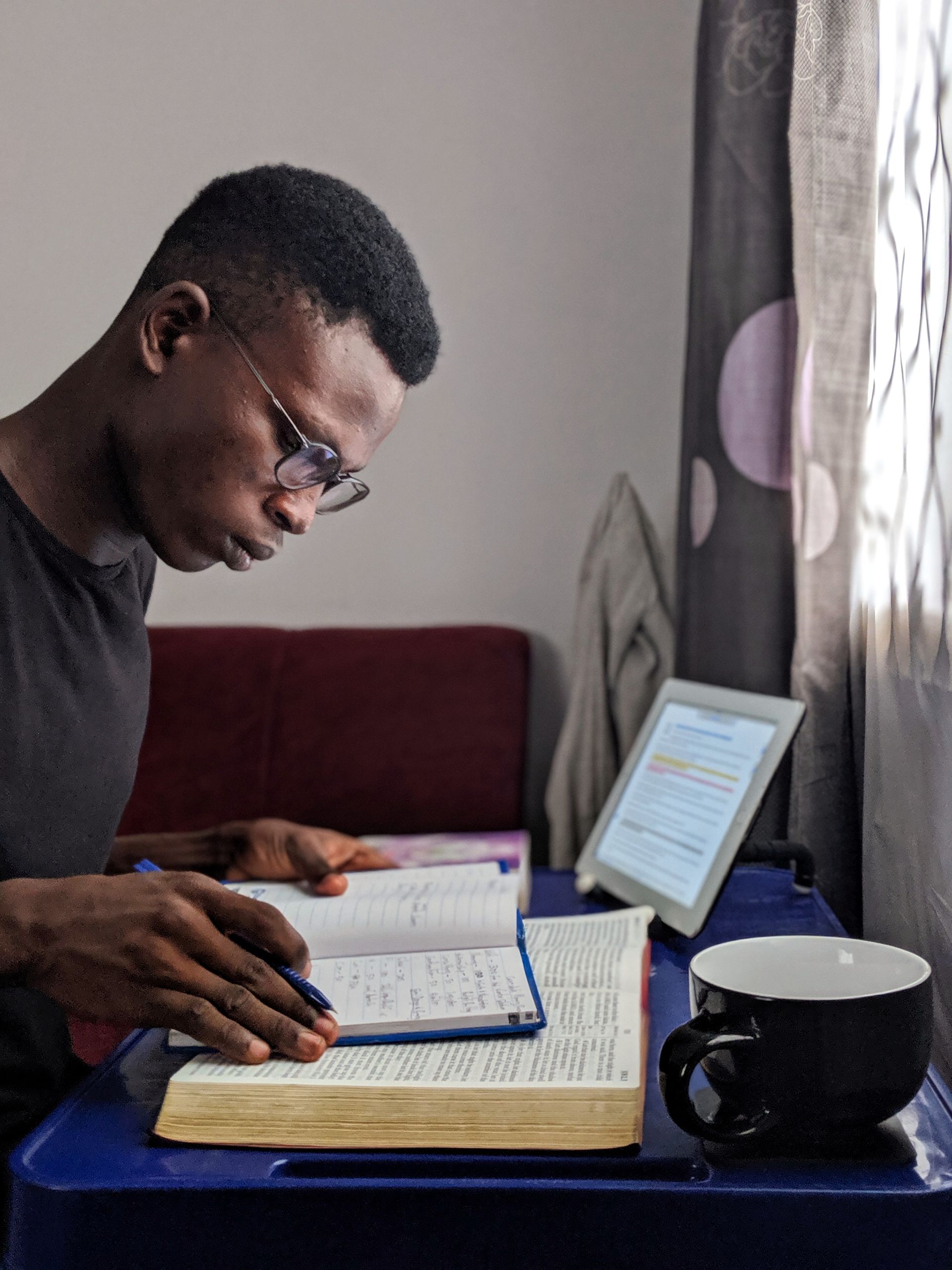 Young man immersed in reading with books and a tablet