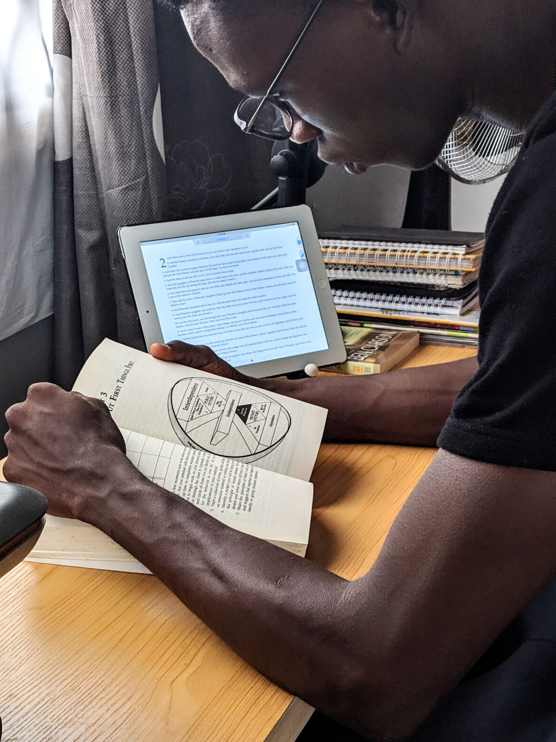 Man studying with a book and tablet at a desk