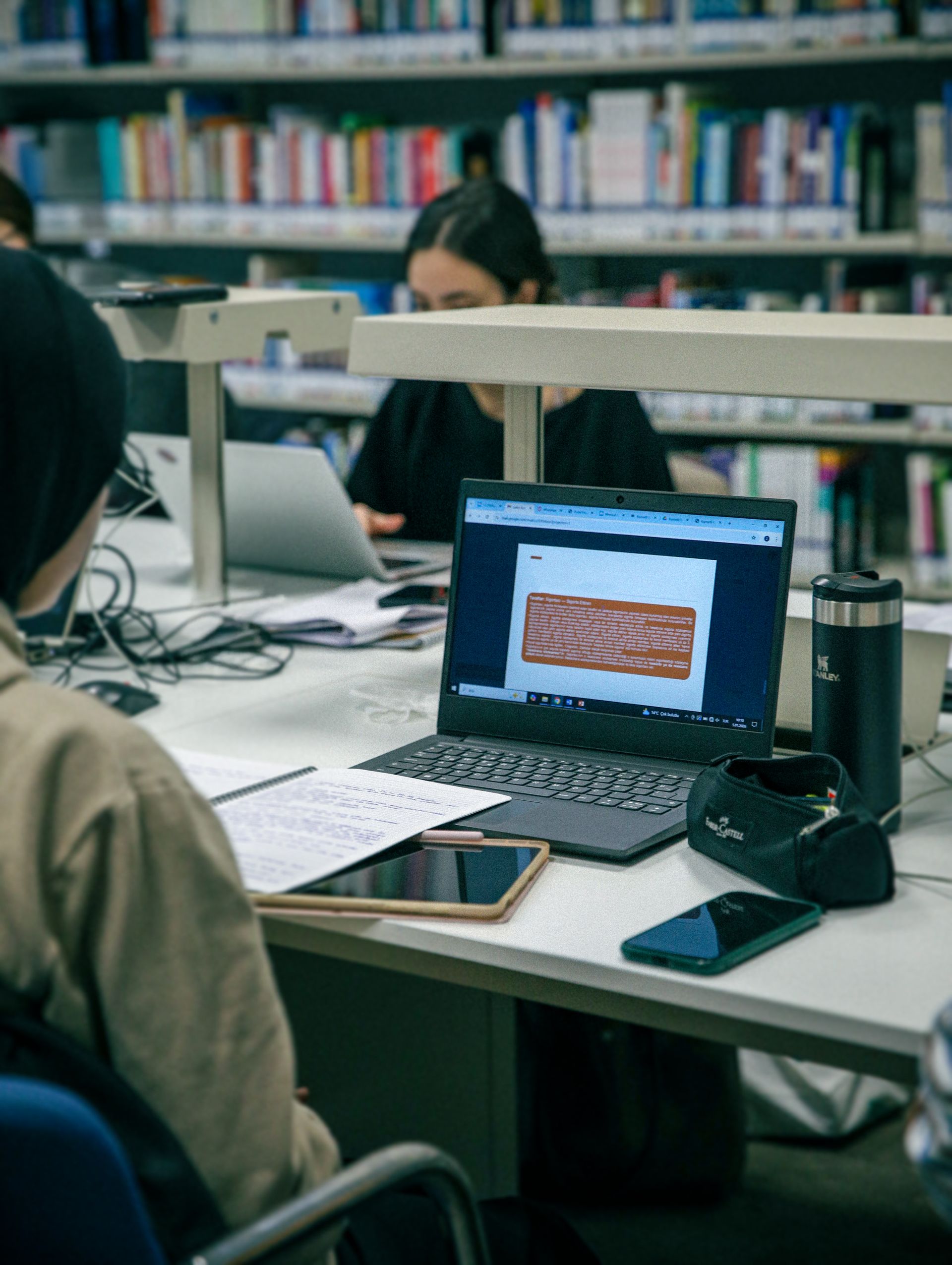 Students studying with laptops and books in a modern library