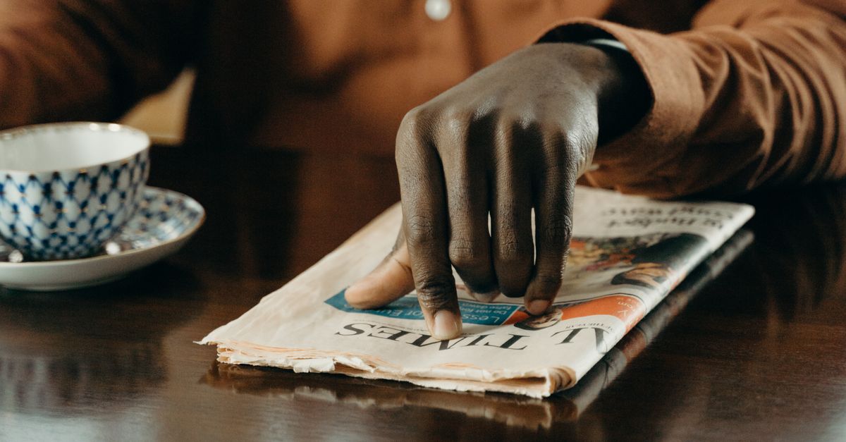 Person with a cup of tea reading a newspaper