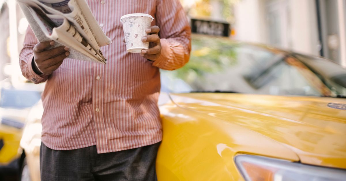 Person holding coffee and a newspaper