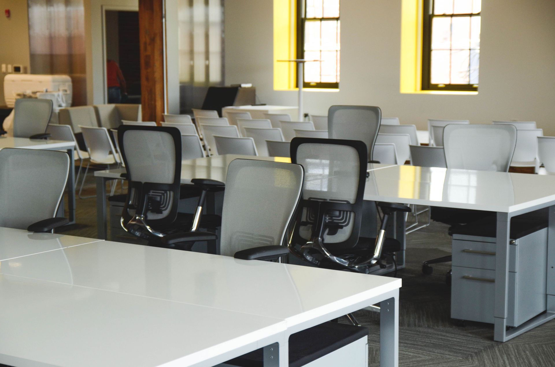 Spacious open office workspace with desks, chairs, and natural lighting