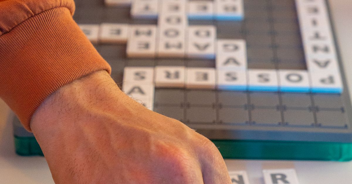 Person playing Scrabble on a white table