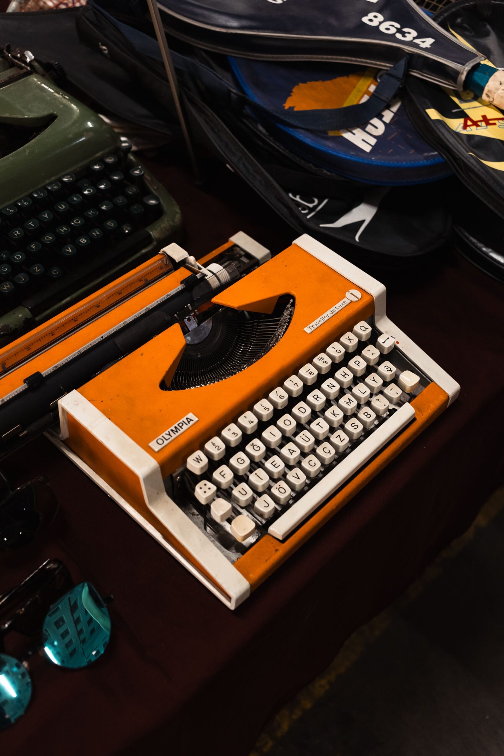An eye-catching vintage orange Olympia typewriter displayed with accessories, capturing retro charm.