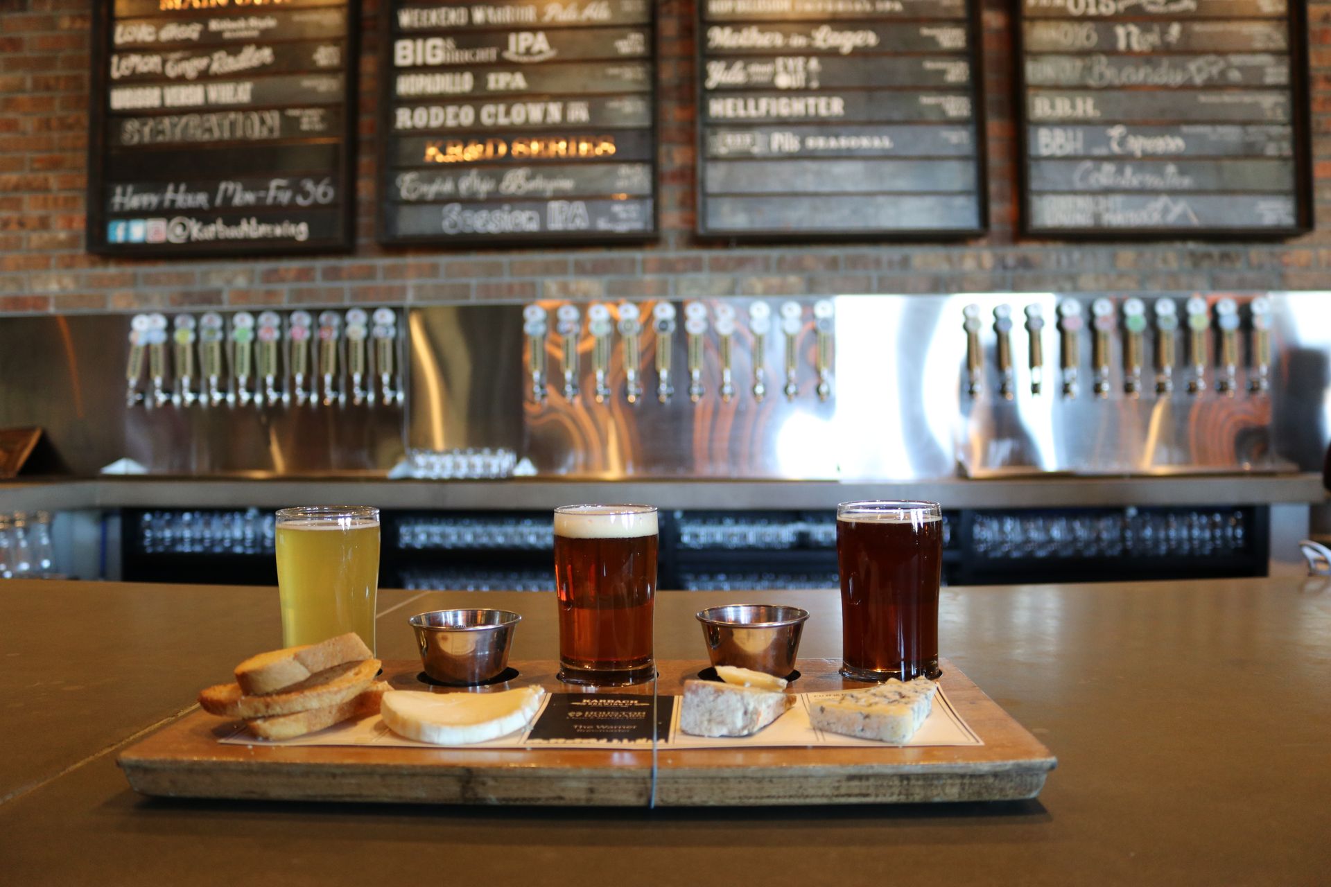 A selection of craft beers served with cheese and bread on a bar counter
