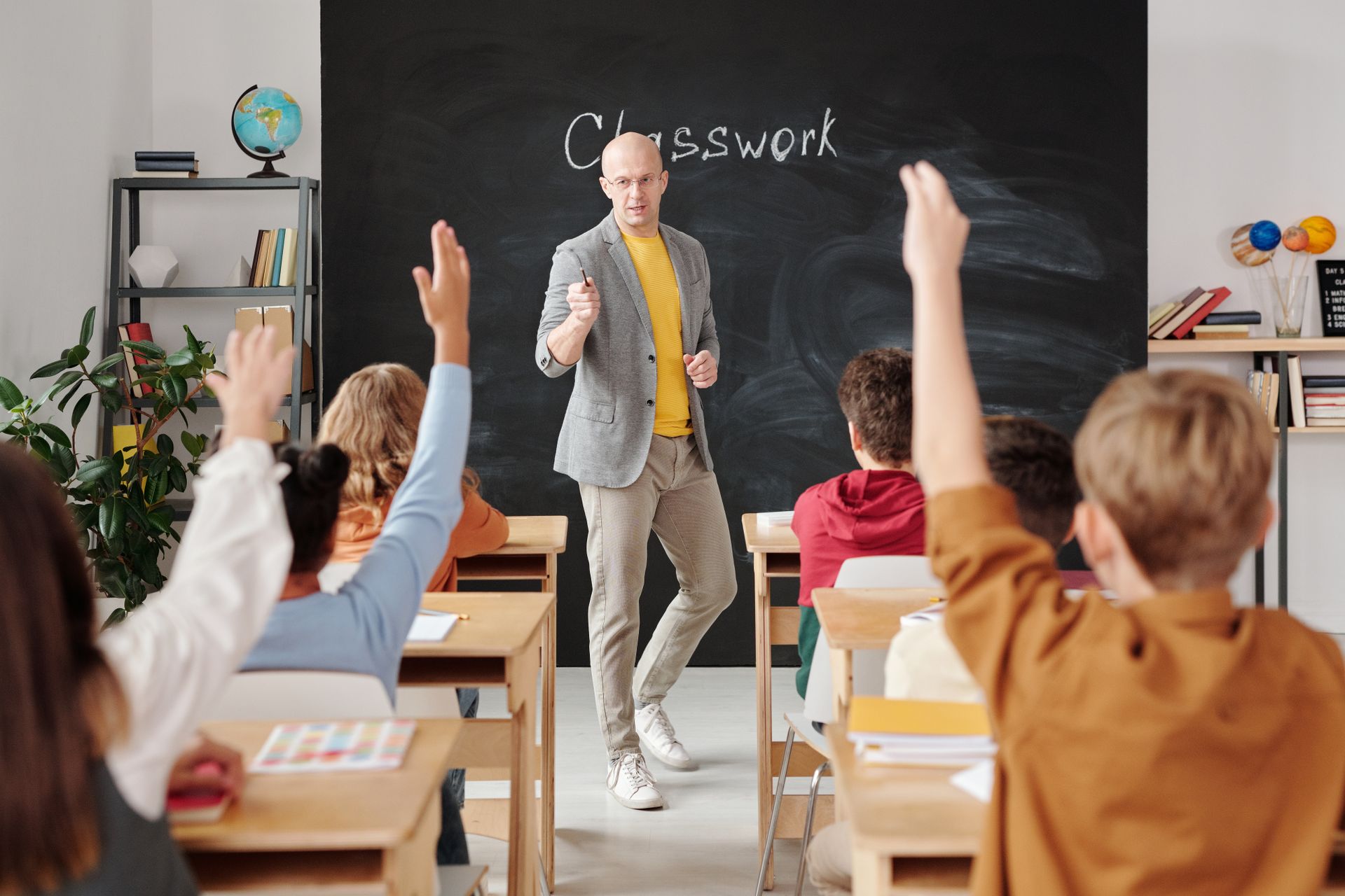 Teacher interacting with students raising hands in class