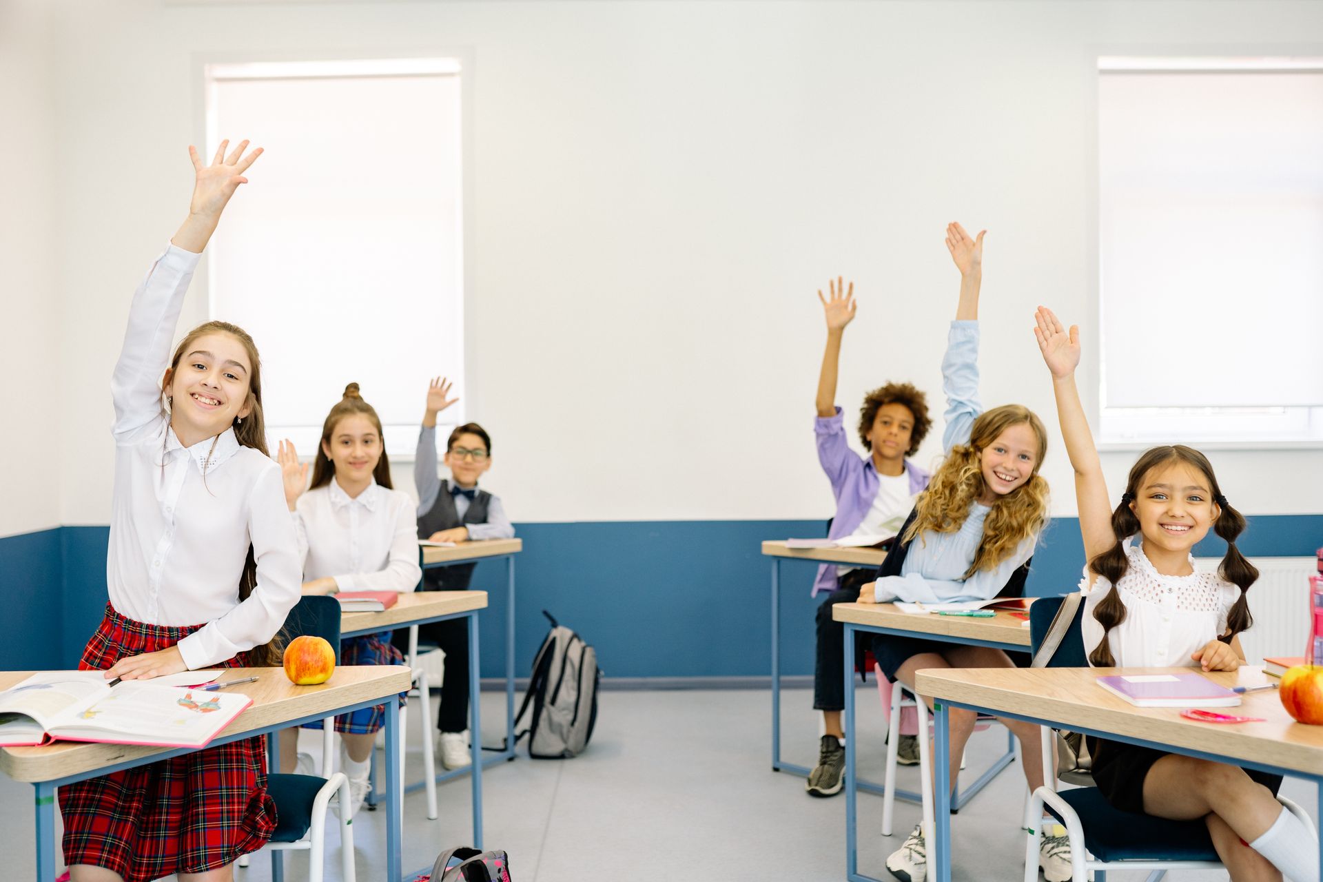 Diverse children eagerly raising hands in a bright classroom