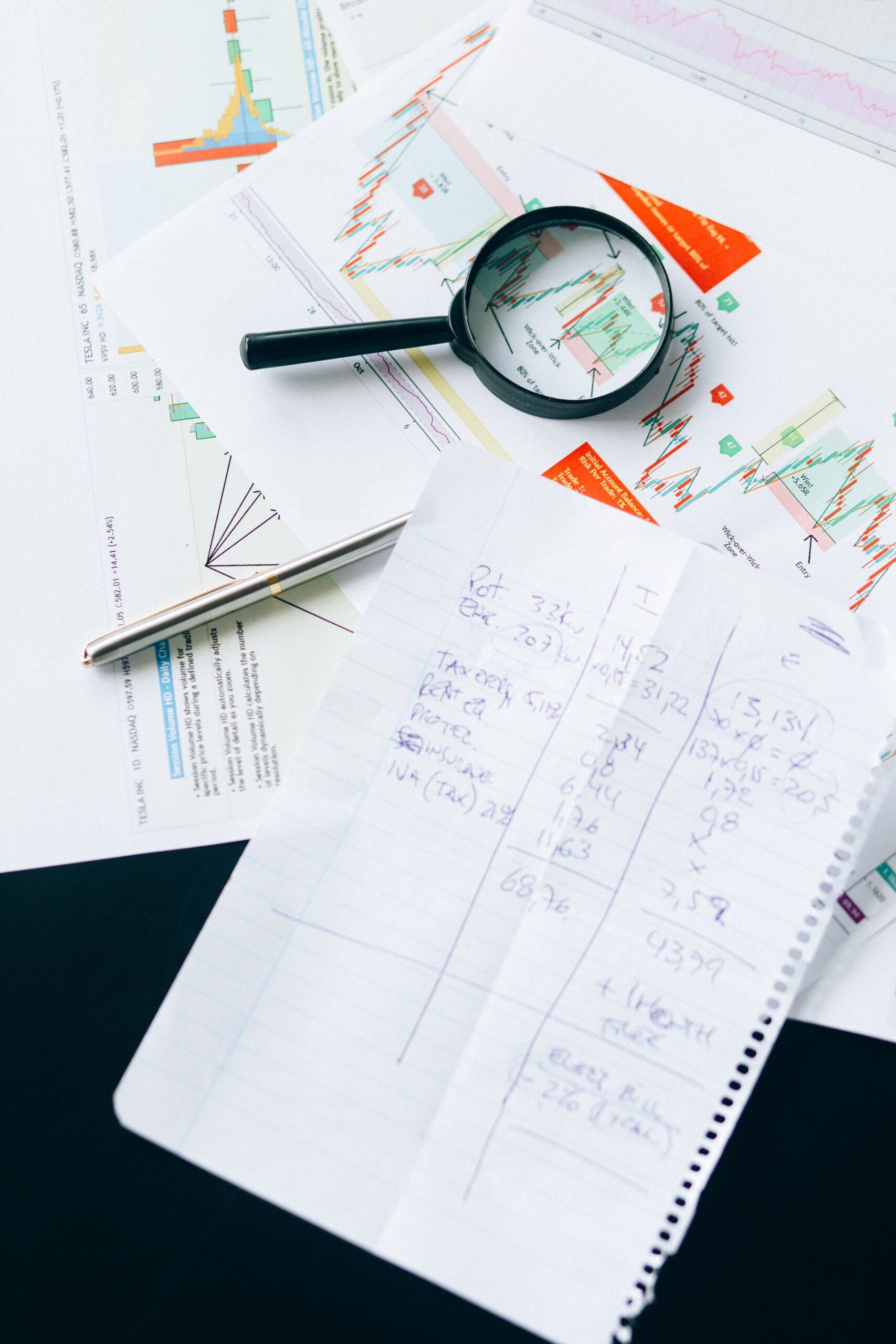 Financial documents and charts with a magnifying glass, symbolizing analysis and data review