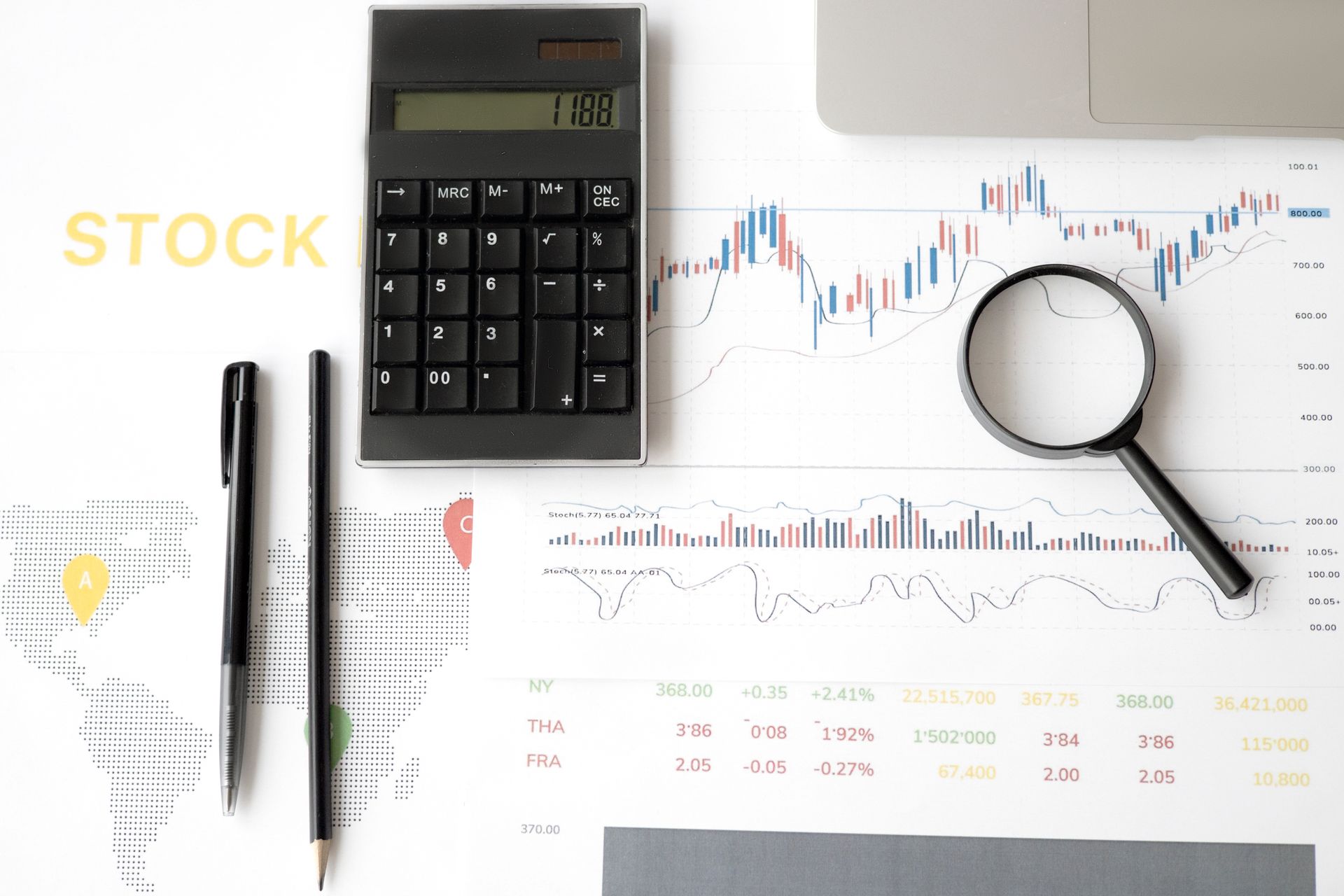 Flat lay of stock market analysis tools including calculator, graphs, and magnifying glass