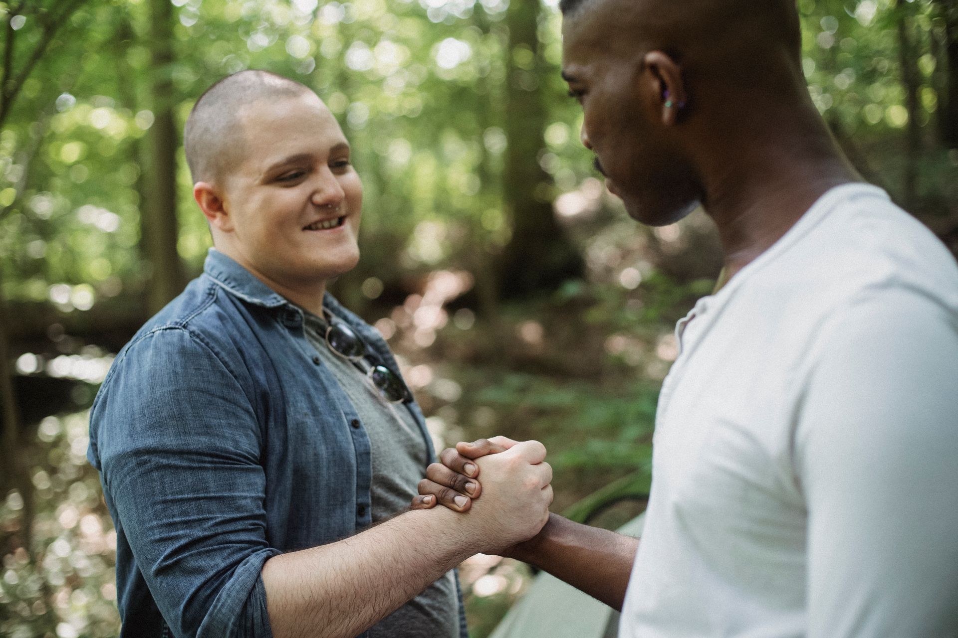 Two friends greeting each other with a handshake in a sunny forest