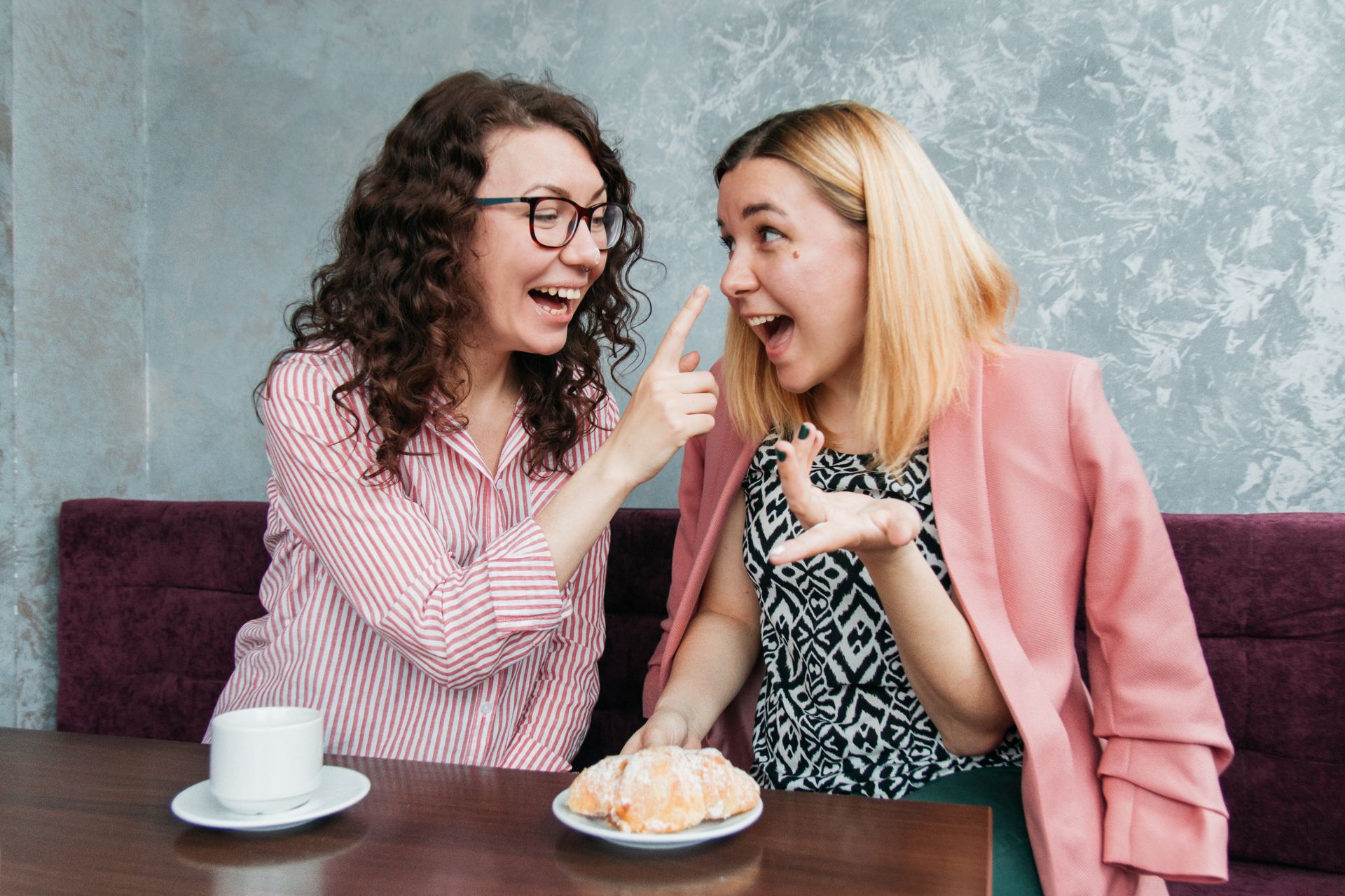 Two women sharing laughter over coffee at a cafe