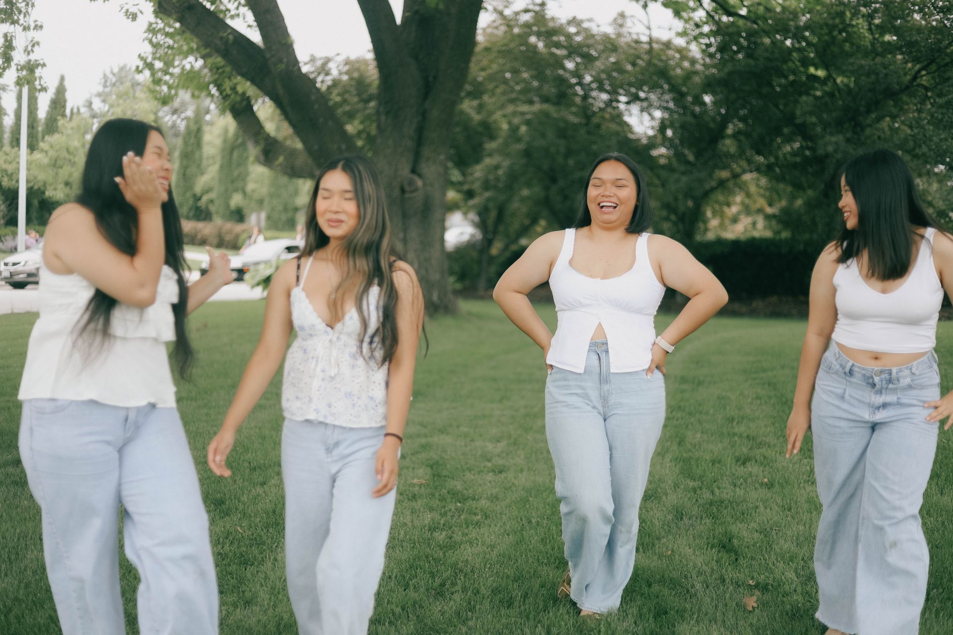 Four friends laughing on a sunny day in a park