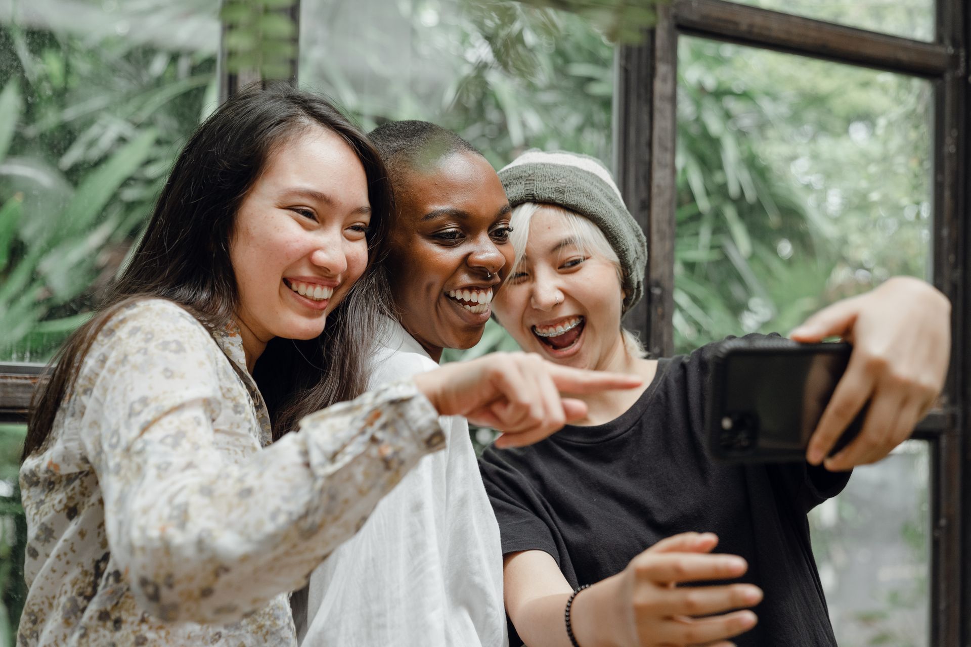 Three friends laughing and taking a selfie indoors