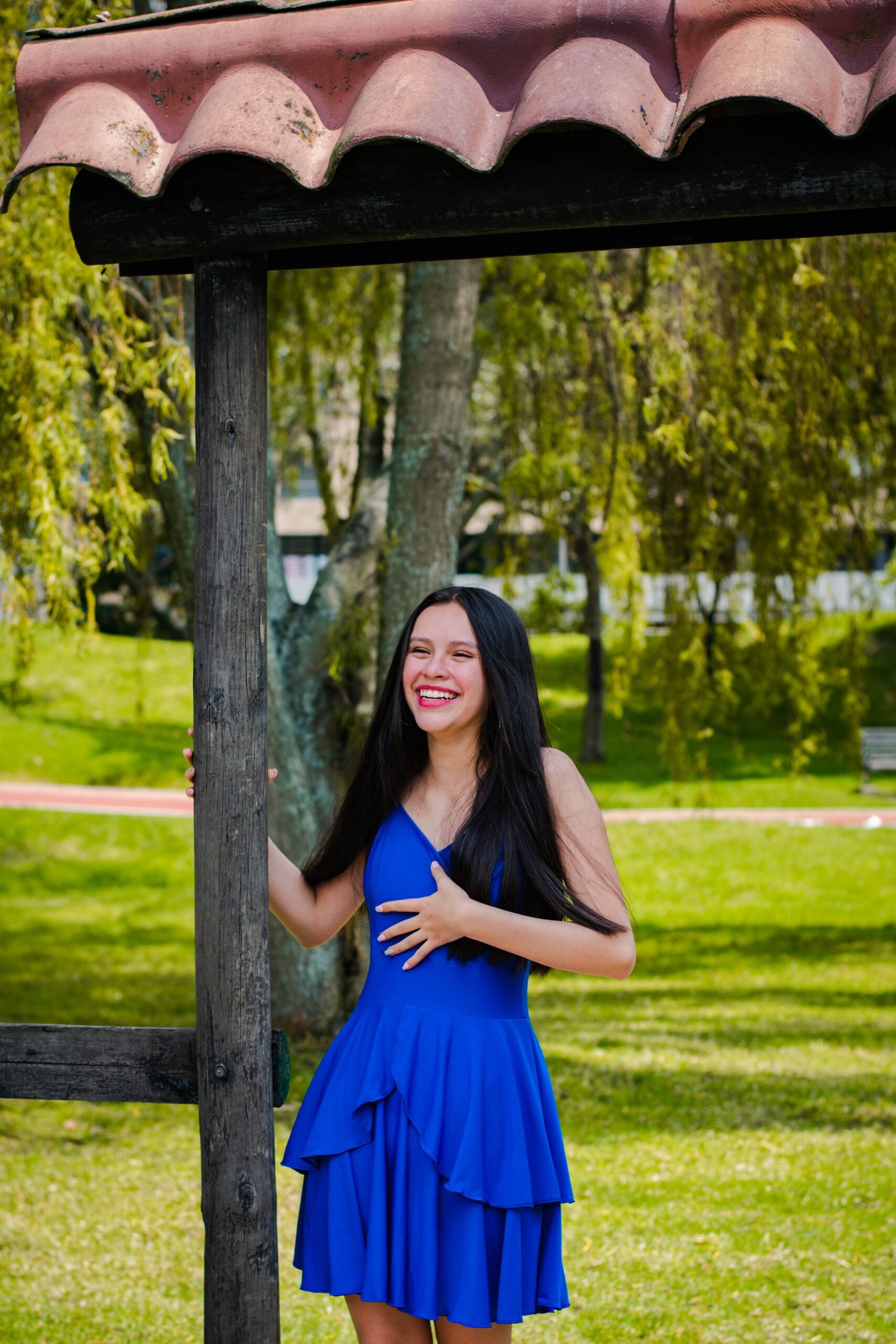 Happy woman in a blue dress laughing in a park