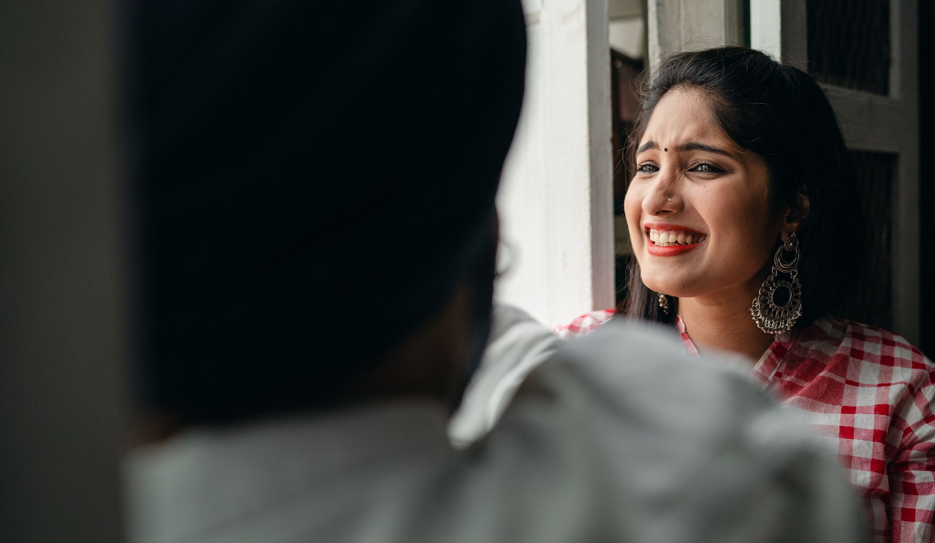 Cheerful woman laughing near a sunlit doorway