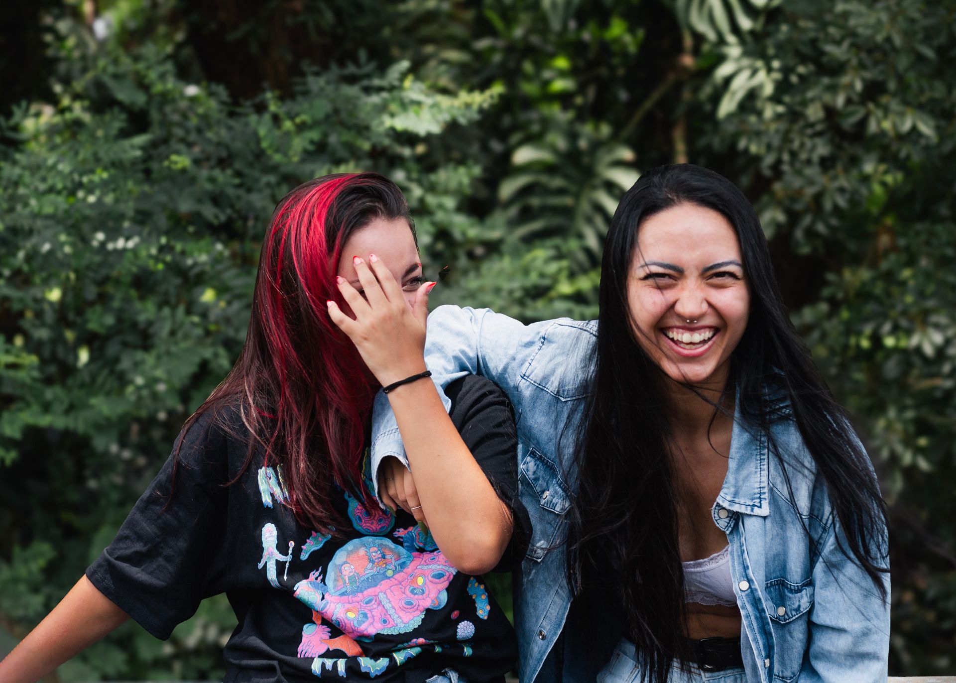 Two young women share a joyful moment outdoors, showcasing friendship and happiness.