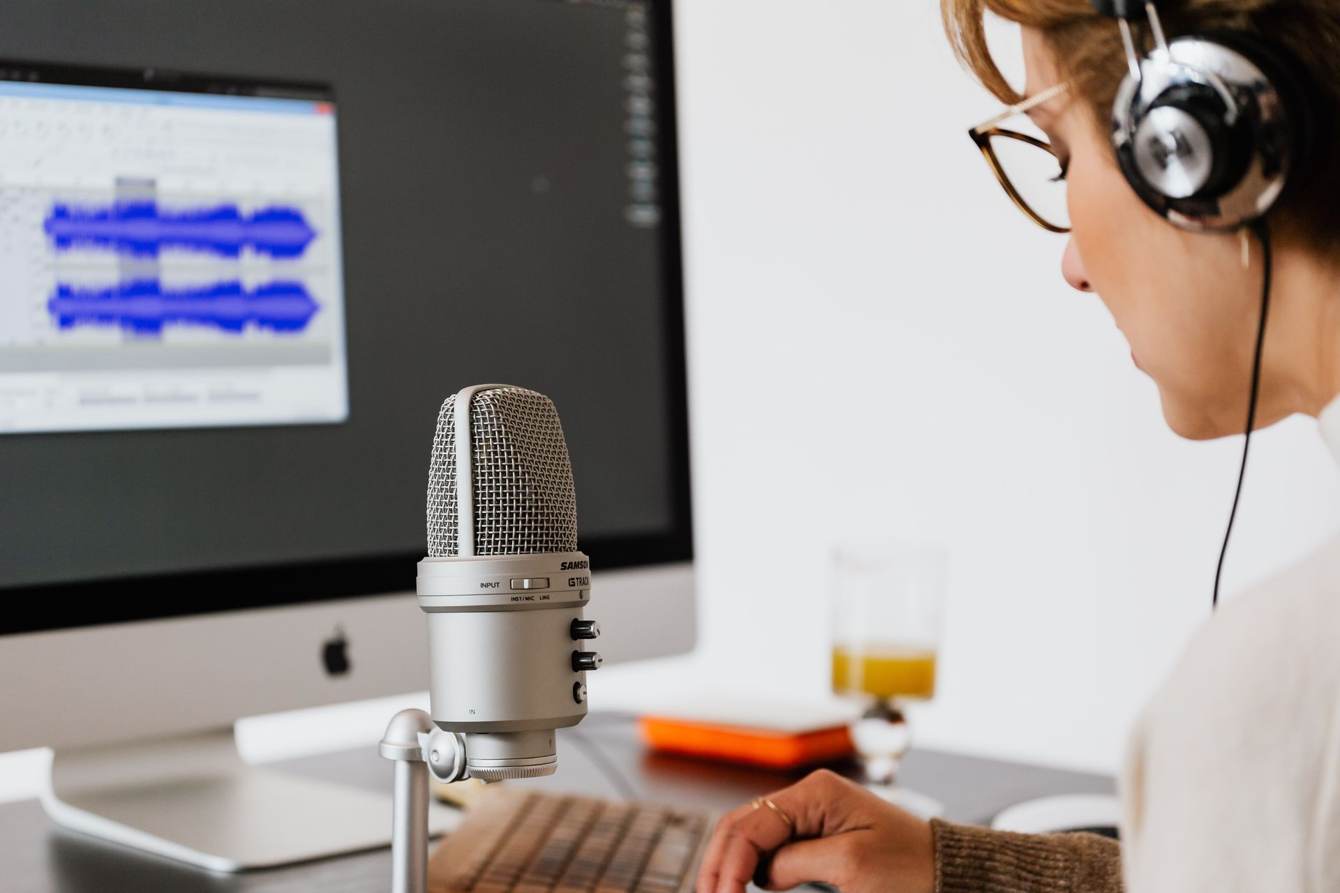 Woman recording audio with a microphone and headphones at a home office