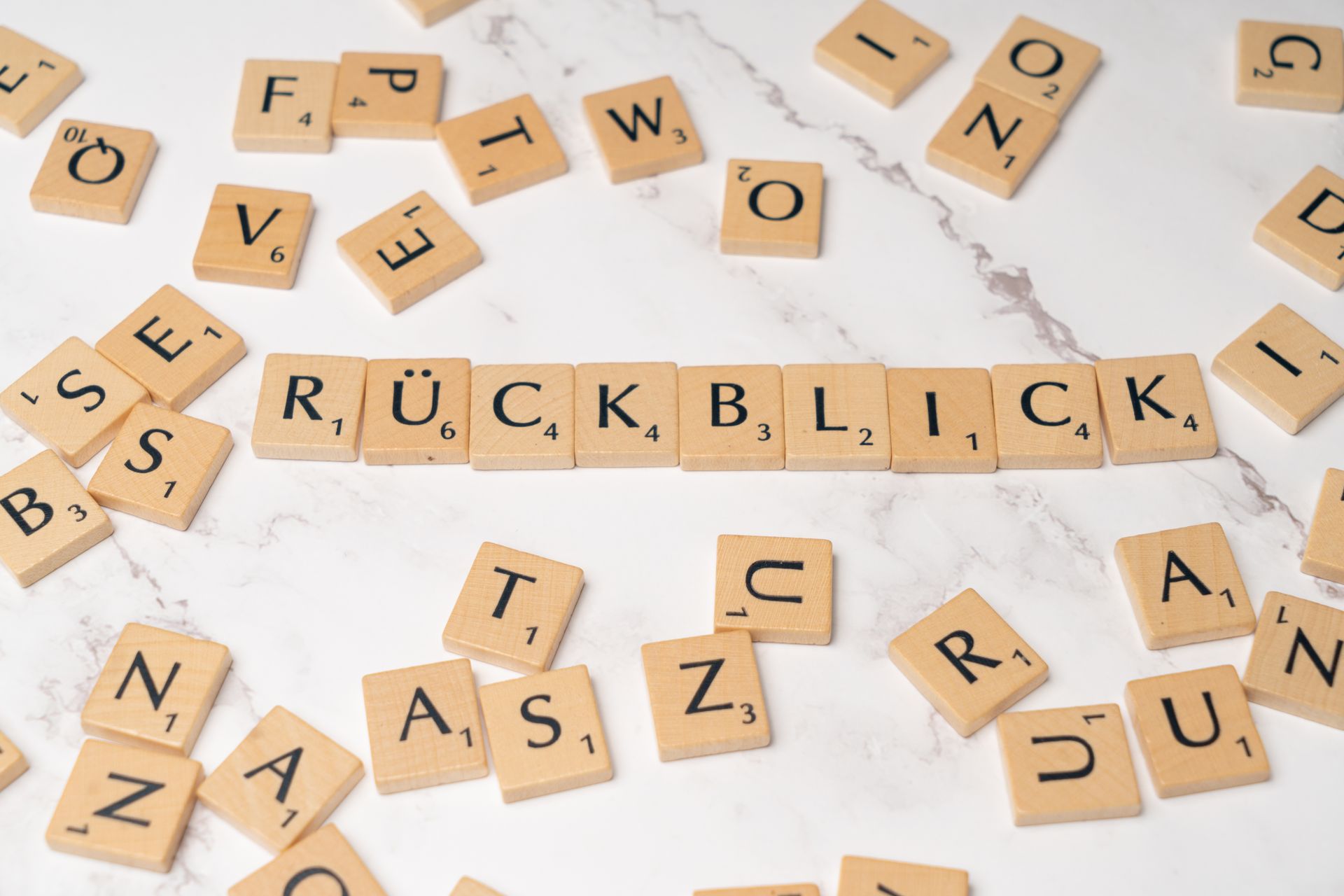 Scrabble tiles spelling Ruckblick with an umlaut on marble