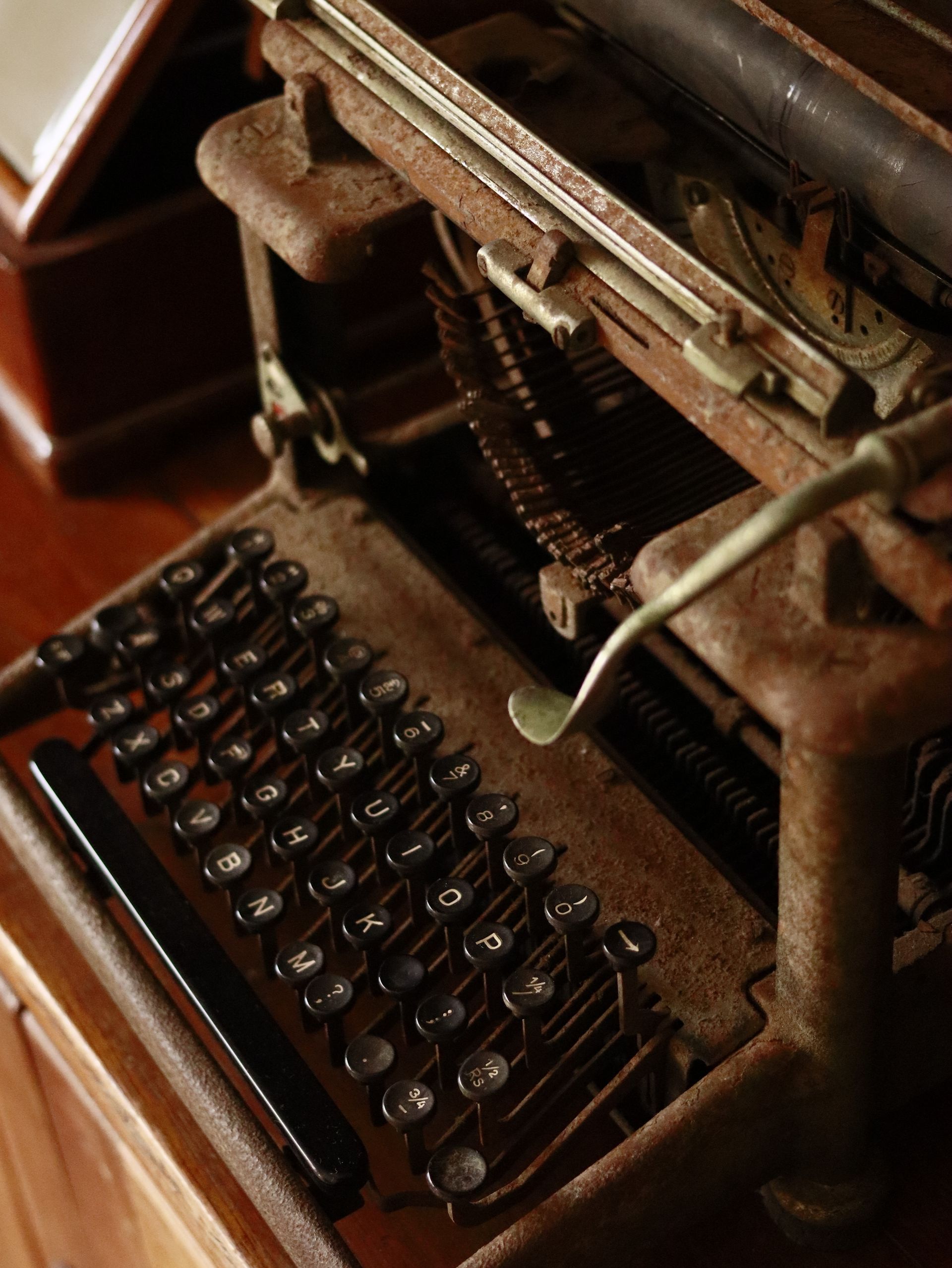 Close-up of an antique typewriter with metal keys on a wooden desk, evoking nostalgia.