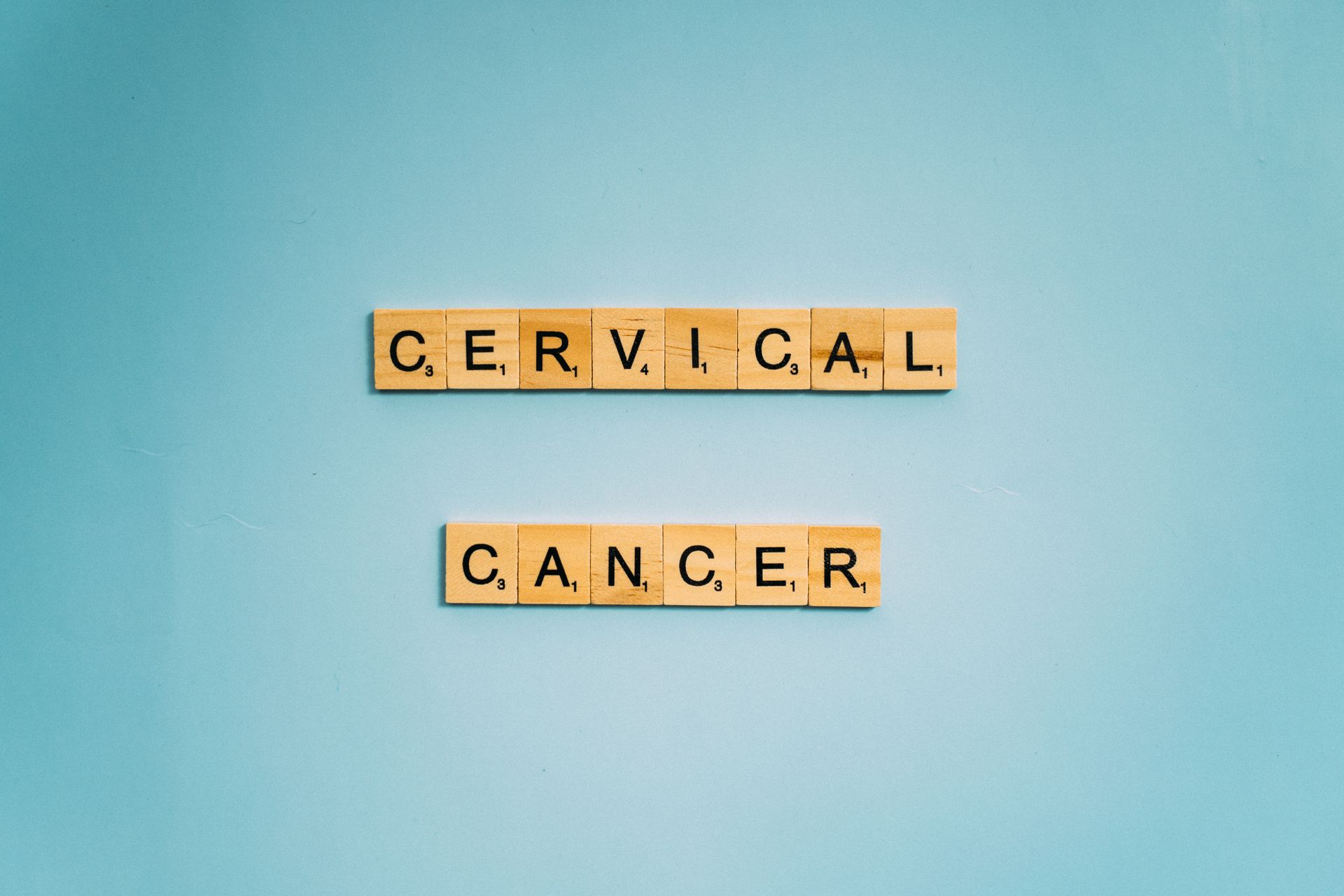 Scrabble tiles spelling 'Cervical Cancer' on a light blue background, symbolizing awareness.
