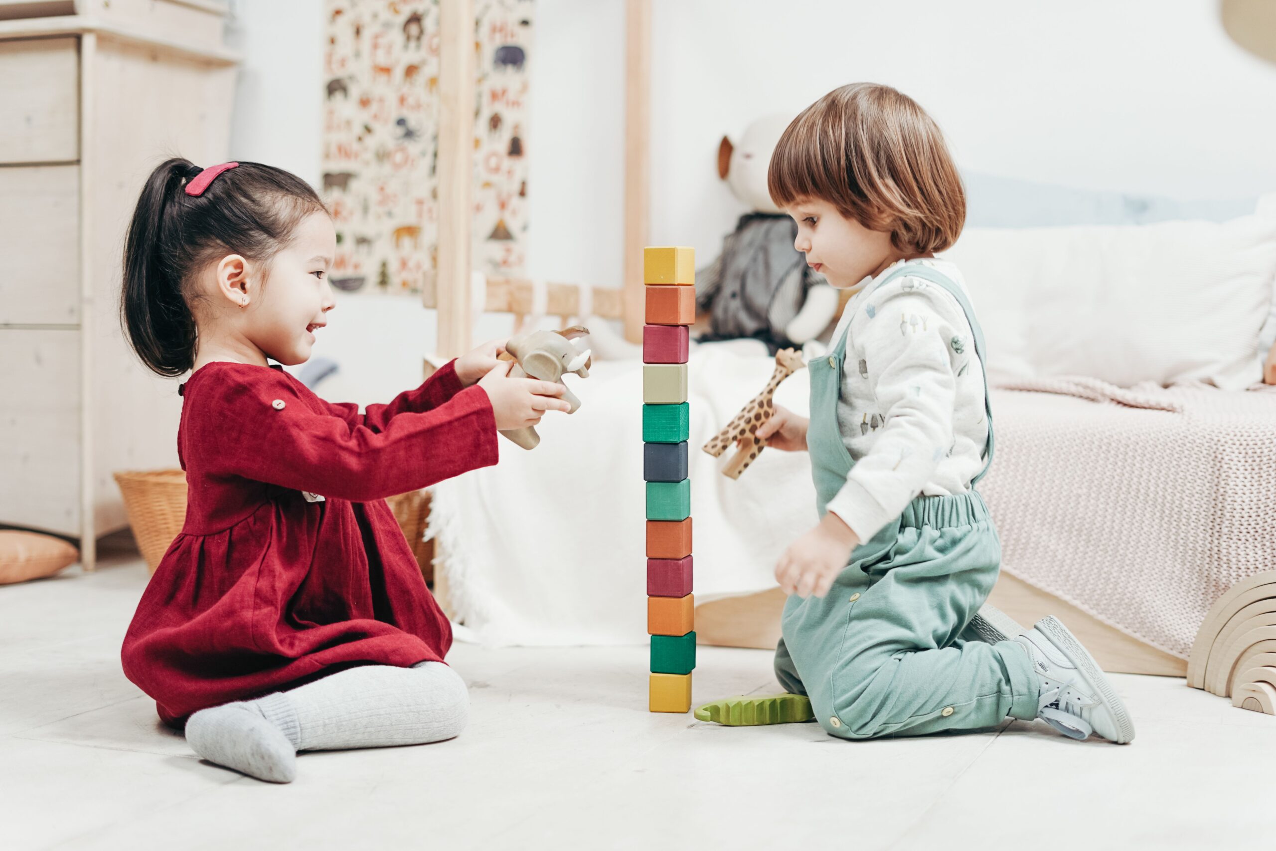 Two young children enjoying playtime with wooden blocks in a cozy indoor setting, fostering creativity and fun.