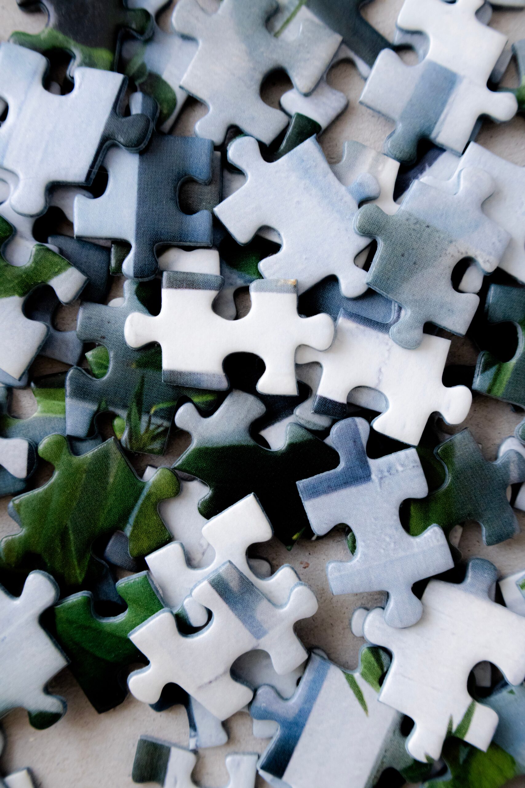 Close-up of jigsaw puzzle pieces scattered randomly on a flat surface.