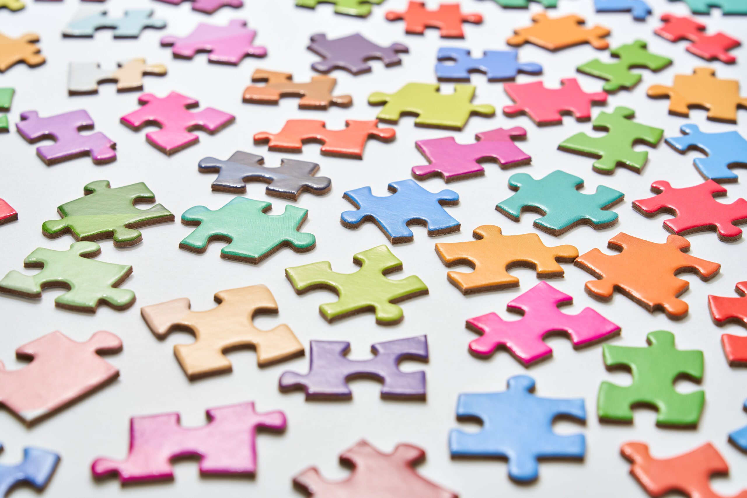 Vibrant jigsaw puzzle pieces scattered on a white background in a still life composition.