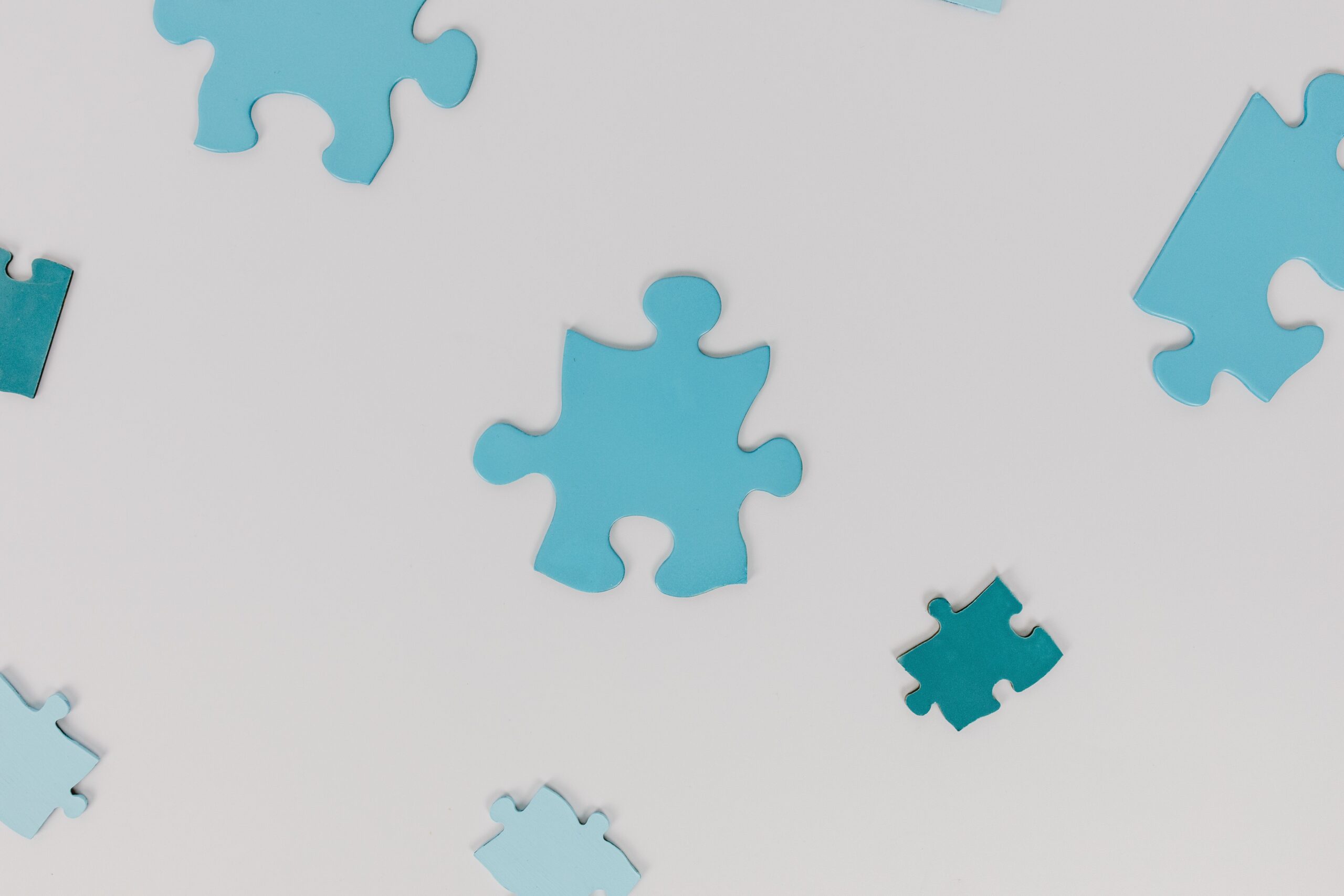 Scattered blue puzzle pieces on a white surface, symbolizing autism awareness.