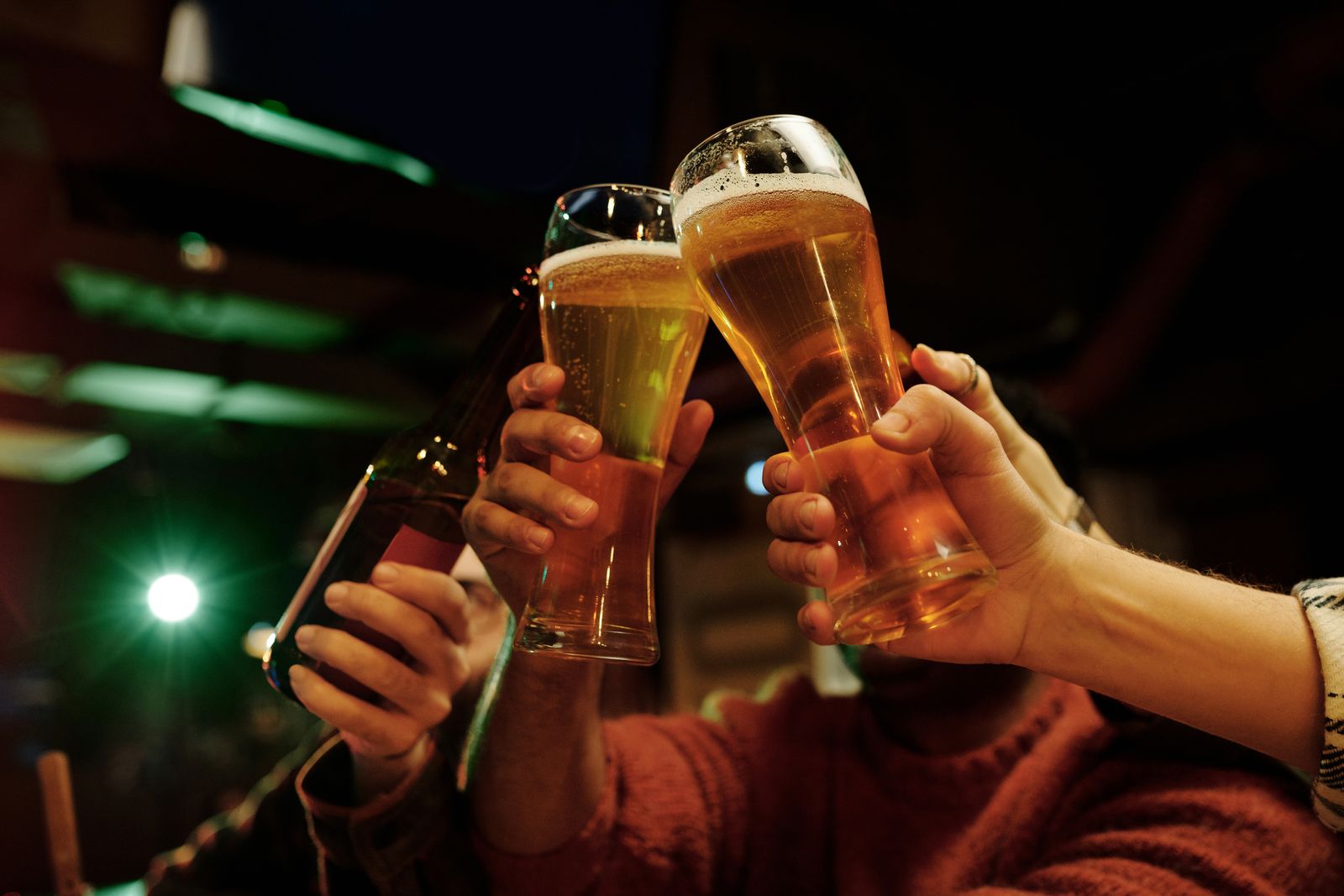 Close-up of friends toasting beer glasses in a bar