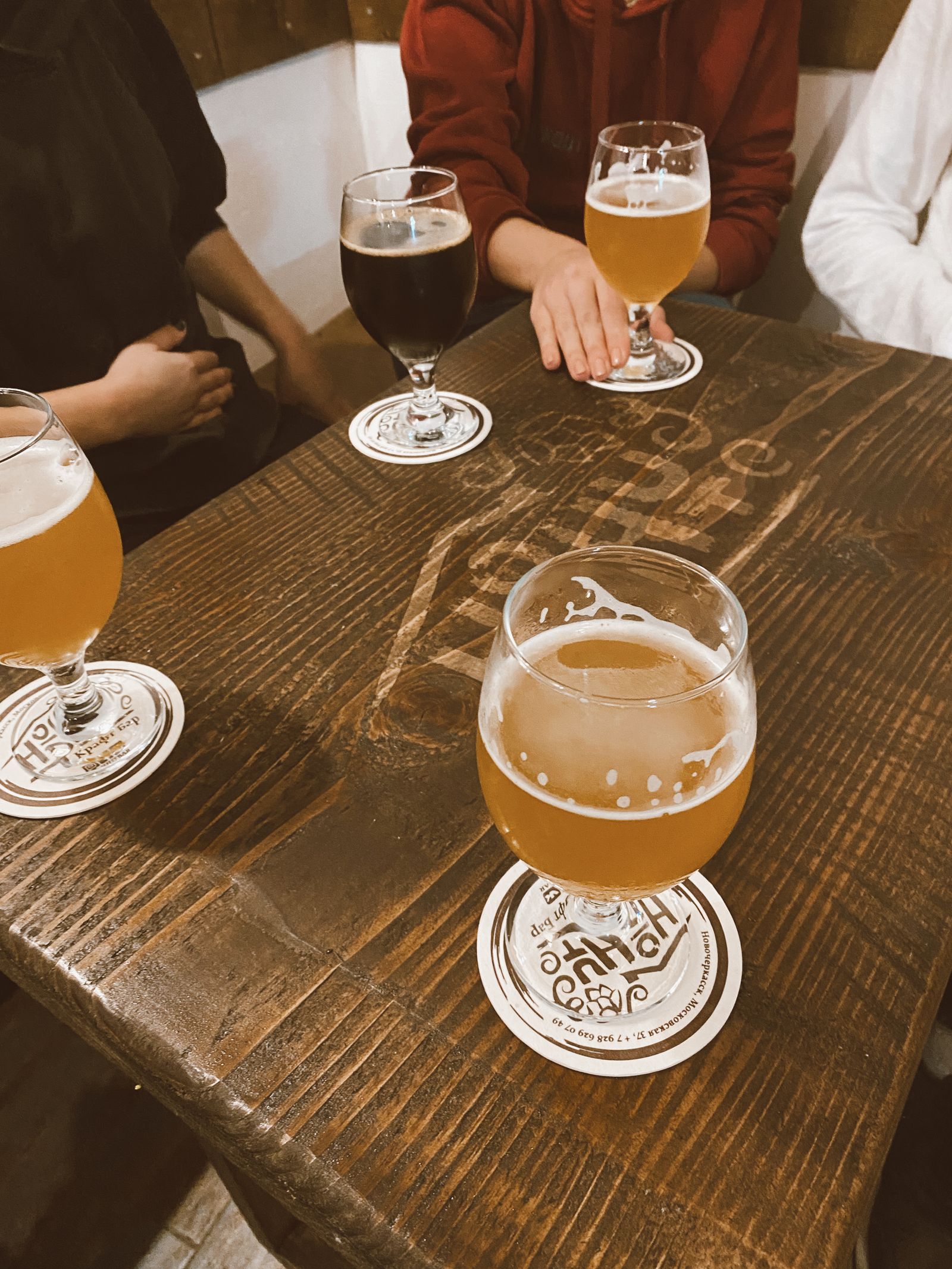 Friends enjoying drinks at a wooden pub table