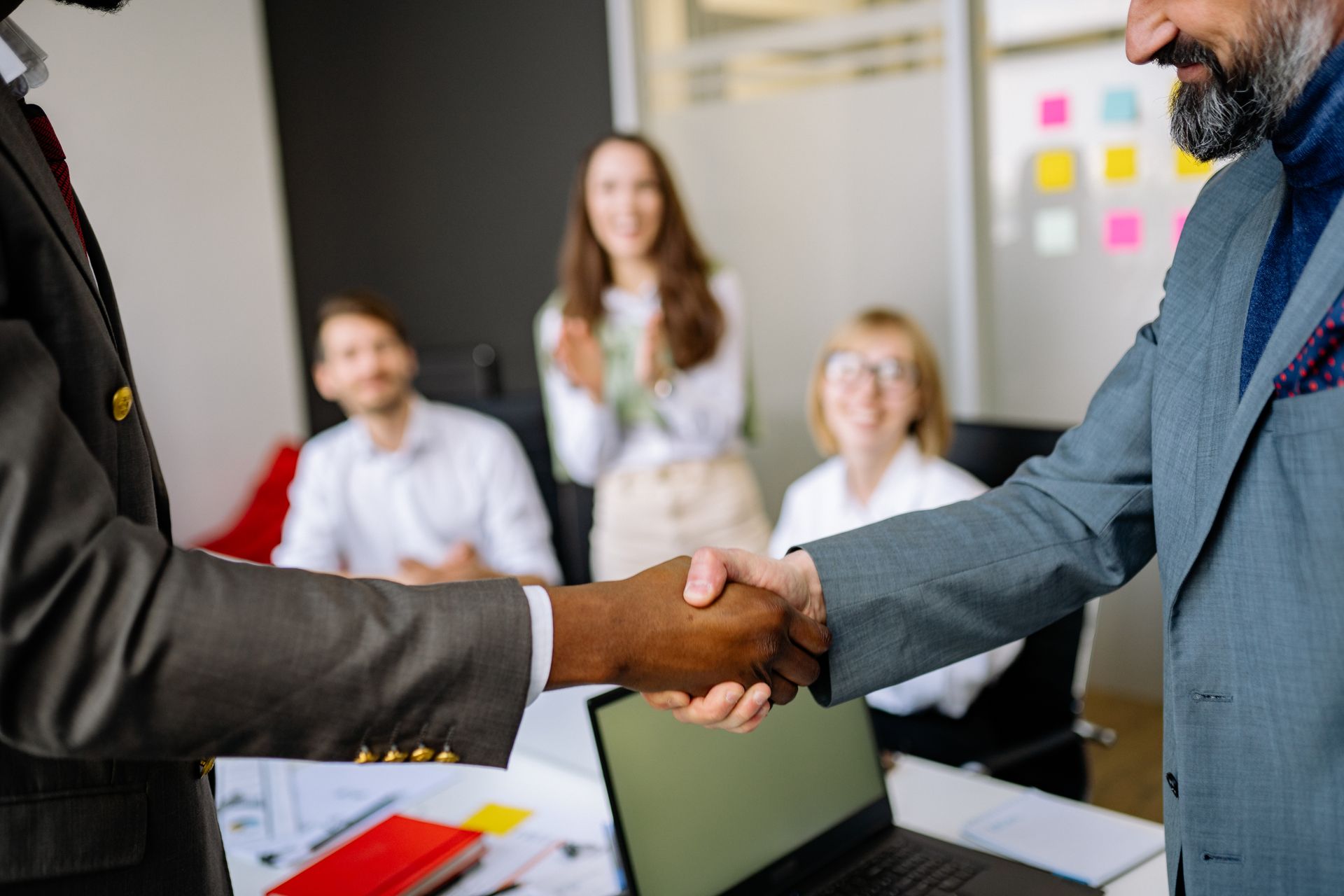 Close-up of a handshake between colleagues in a professional office setting, emphasizing teamwork and agreement