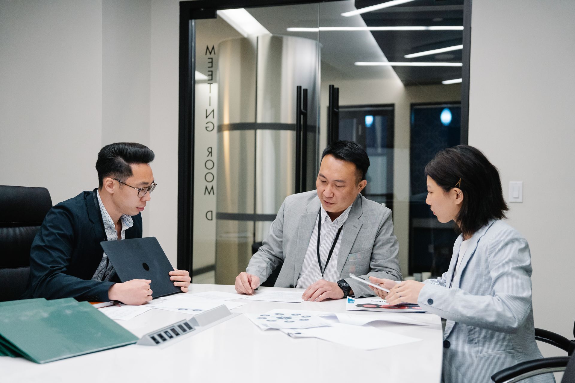 Business meeting with three professionals collaborating in a modern conference room setting