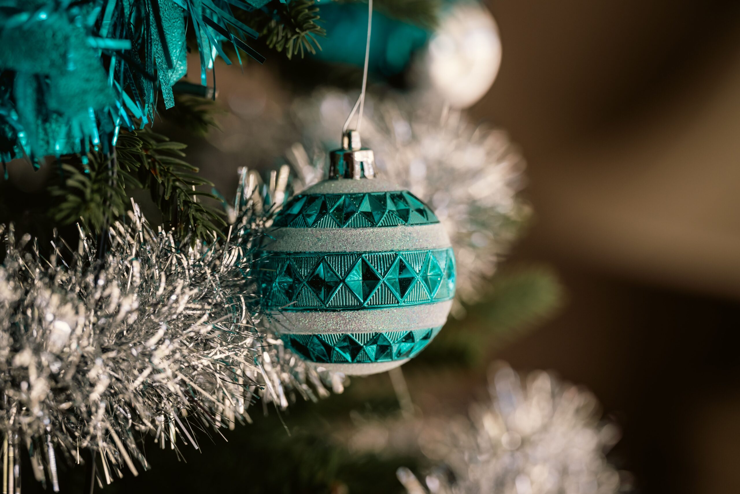 Close-up of blue ornament and silver garland on a Christmas tree indoors.