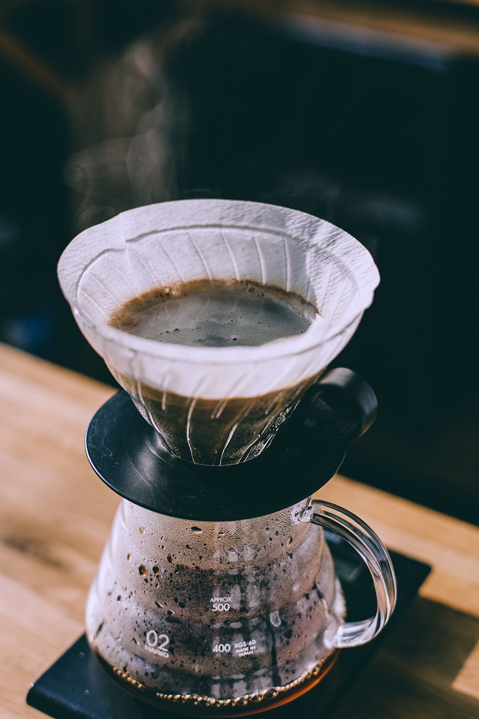 Hot pour-over filter coffee brewing and dripping into a glass pot in a cafe