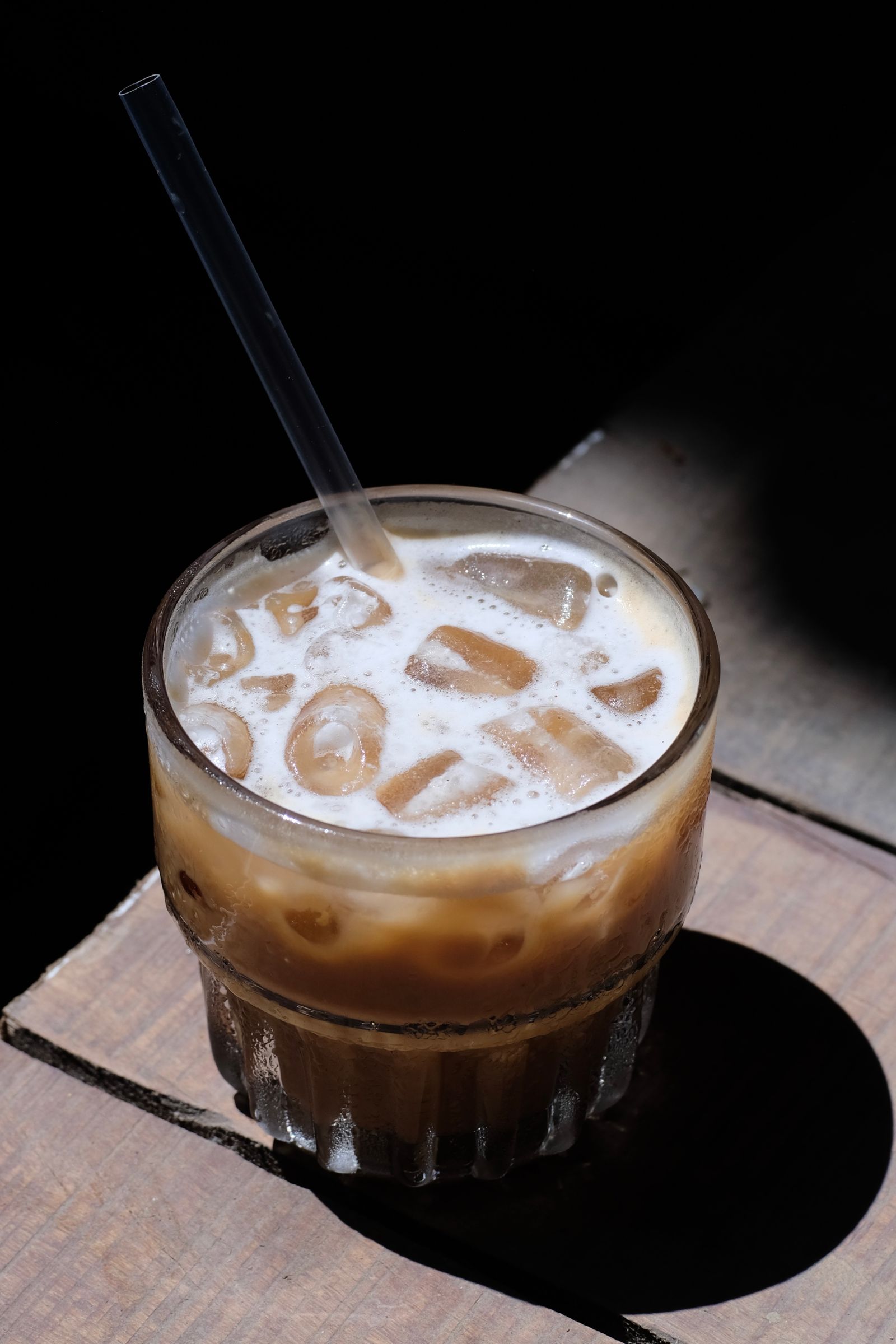 Close-up of iced coffee in a tall glass on a wooden surface
