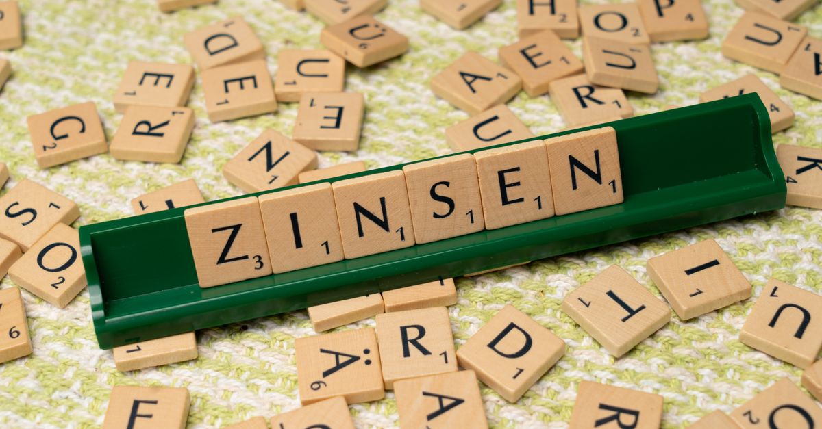 Scrabble tiles spelling the German word Zinsen on a green tray