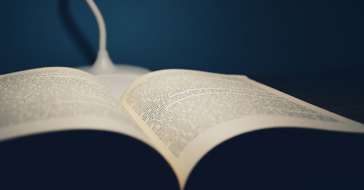 Open book on a table under the glow of a desk lamp