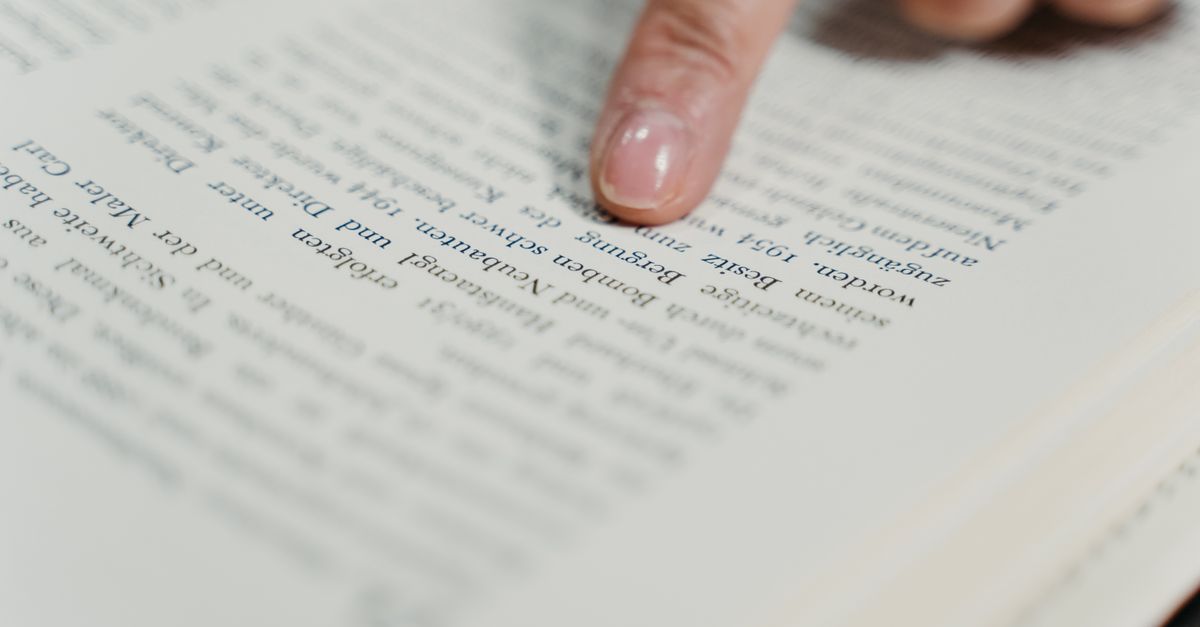 Finger pointing at text on a book page