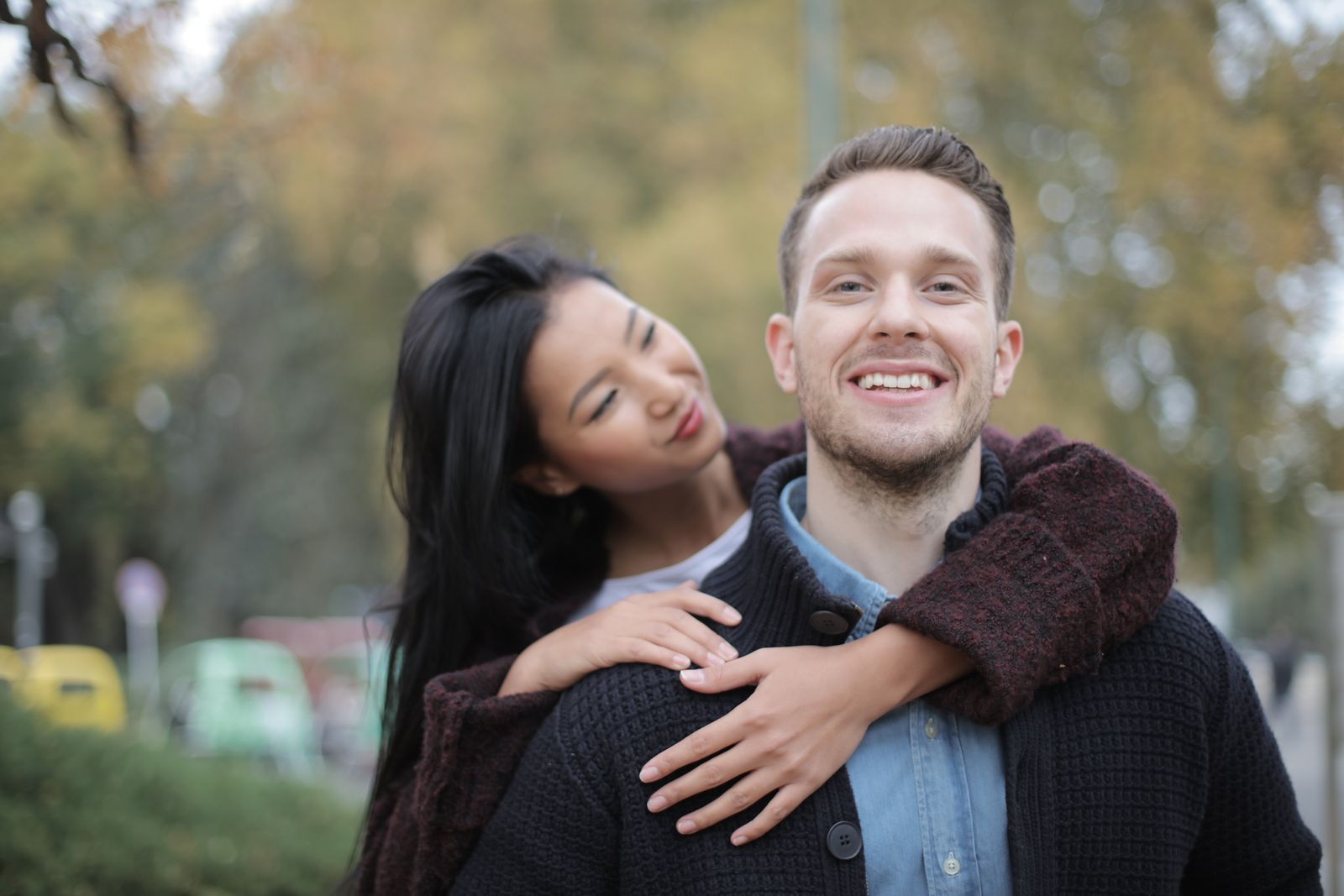Joyful multiracial couple embracing outdoors in an autumn park, radiating happiness and connection